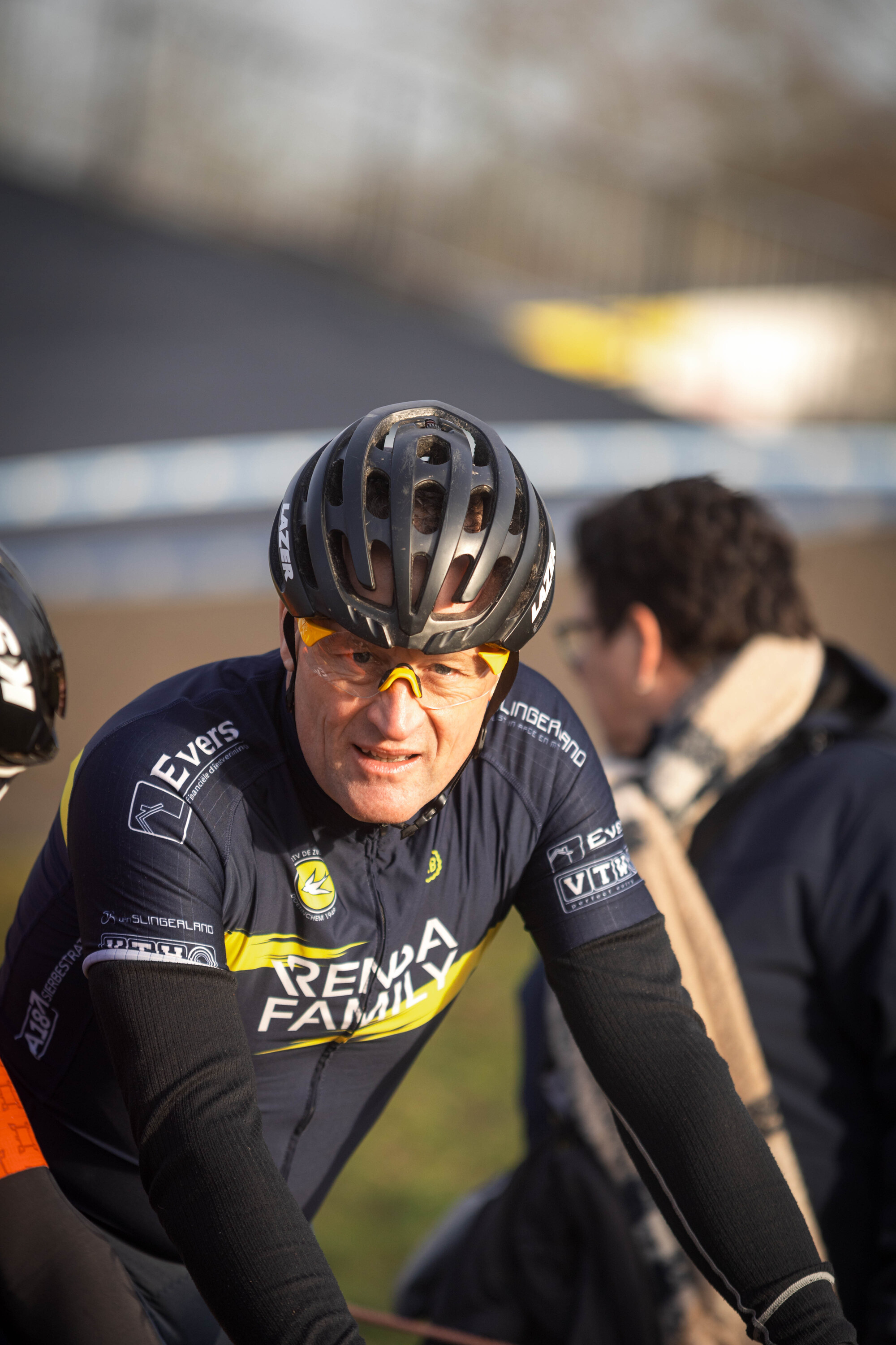 A man in a blue Rema family shirt is riding his bicycle with the yellow and black logo on it.