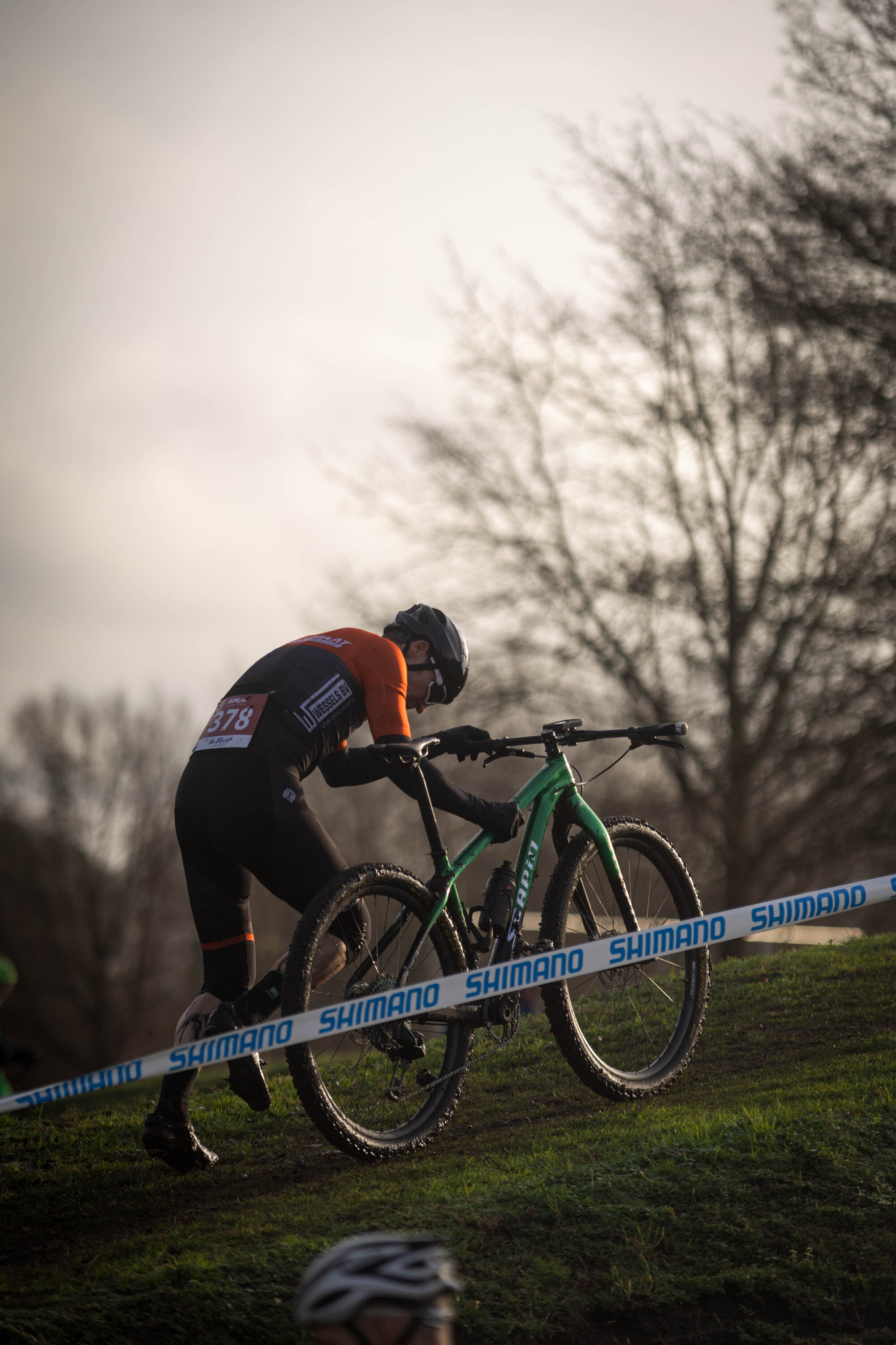 A man is racing on a green bike in a cycling event.