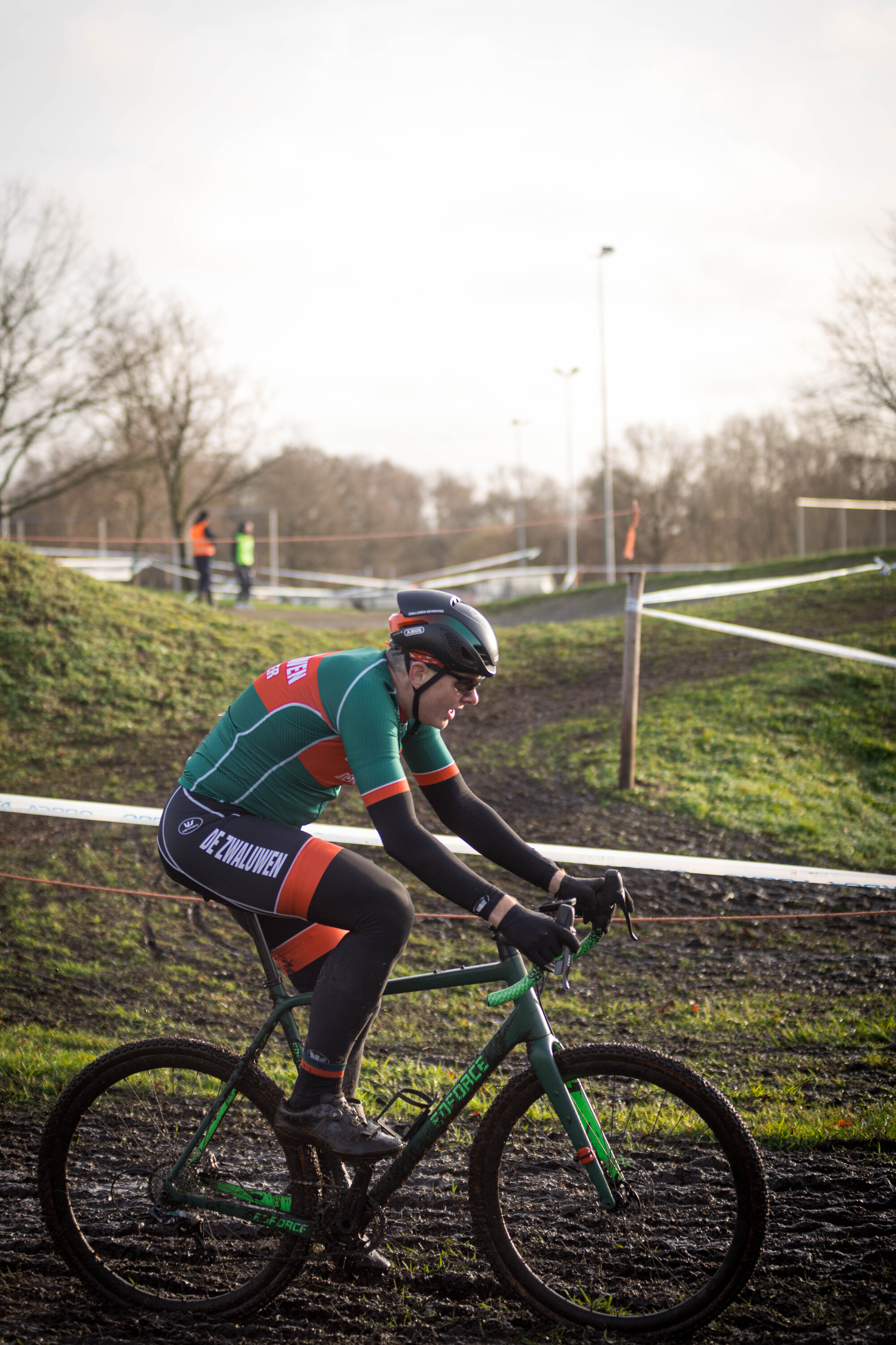 A cyclist in a green and red uniform on a black bike with the number 17 on his uniform.