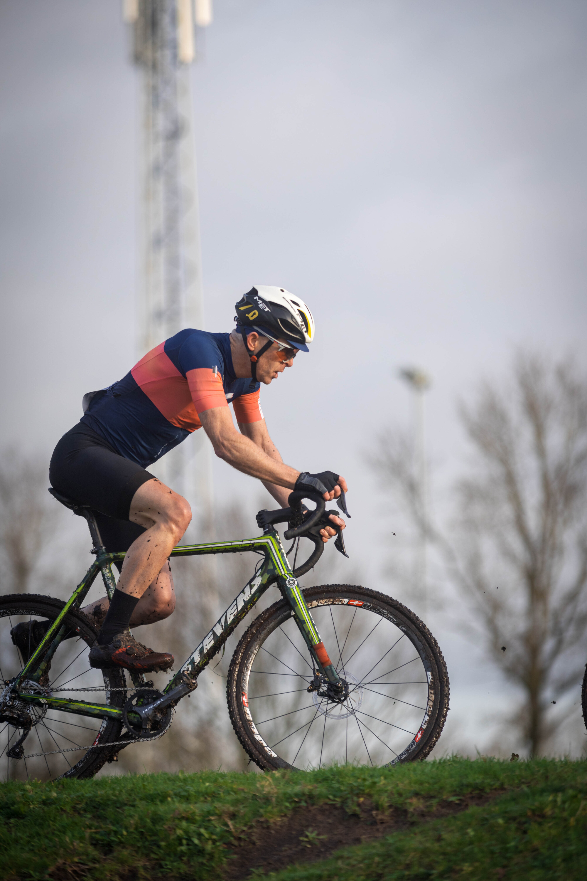 A cyclist wearing a blue and pink shirt on his bike.