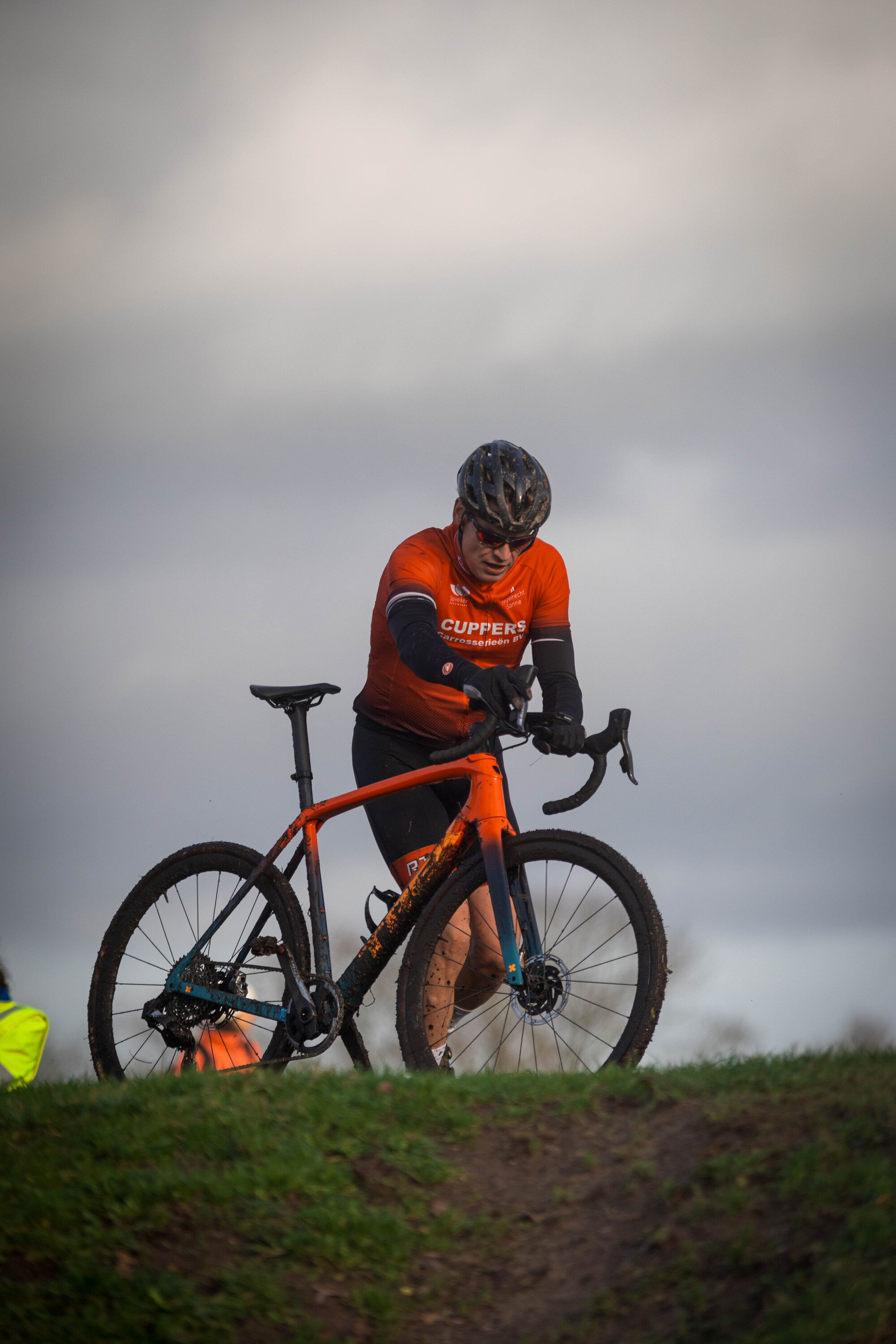 A person in a black helmet is wearing an orange shirt with GOW on it. They are riding a mountain bike.