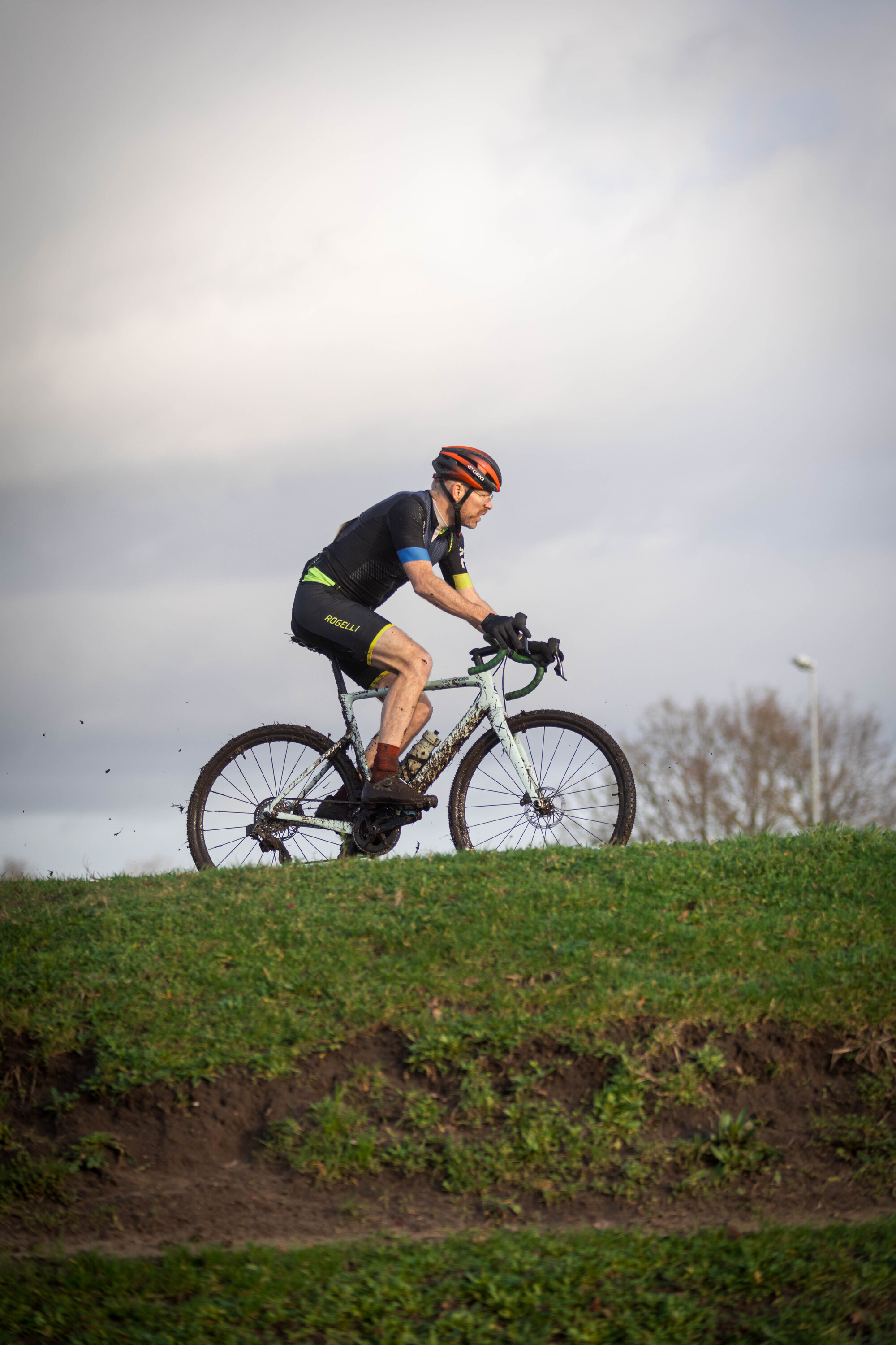 A person on a bike in front of a blue sky with clouds.