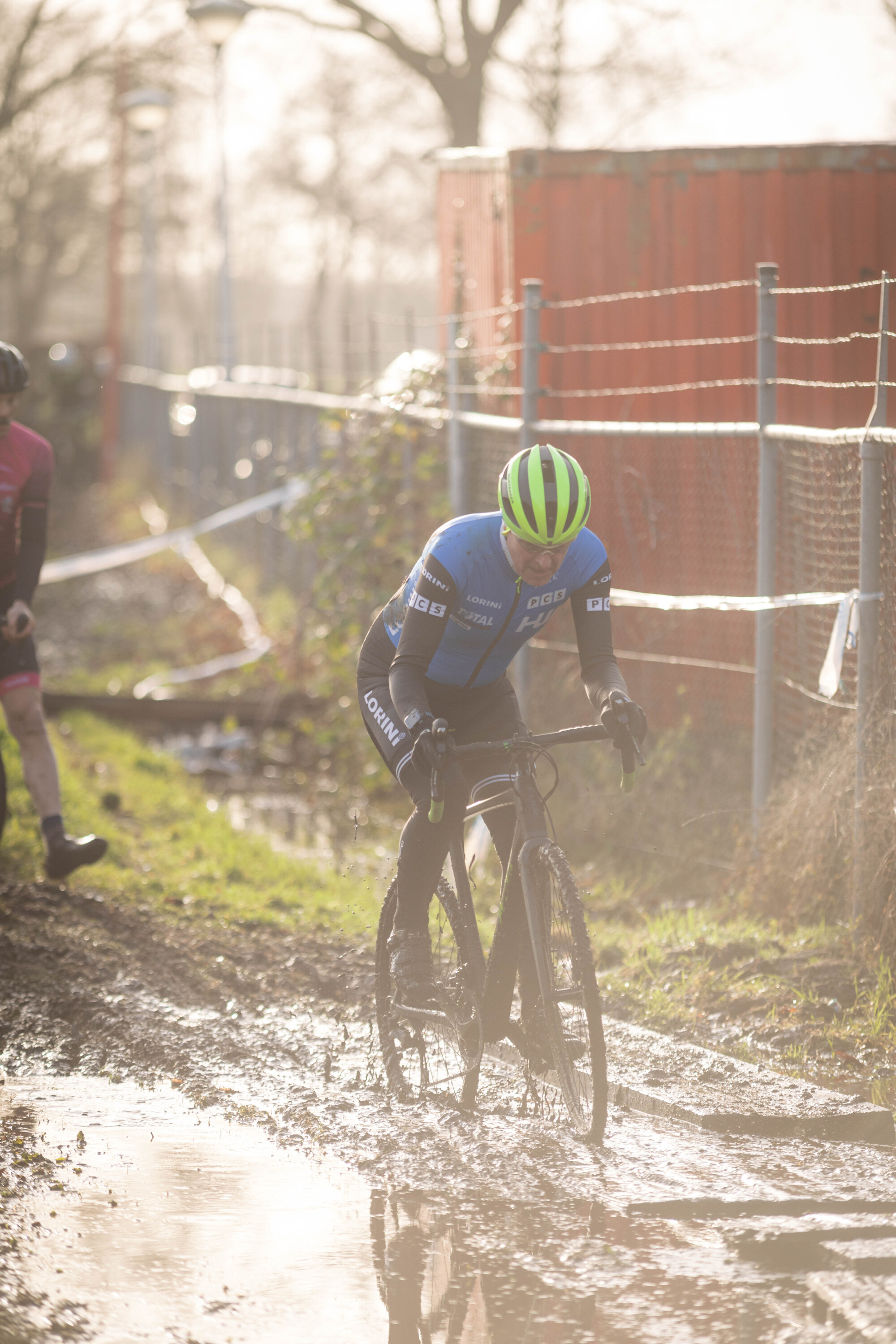 A man in a blue shirt and green helmet is riding a bicycle.