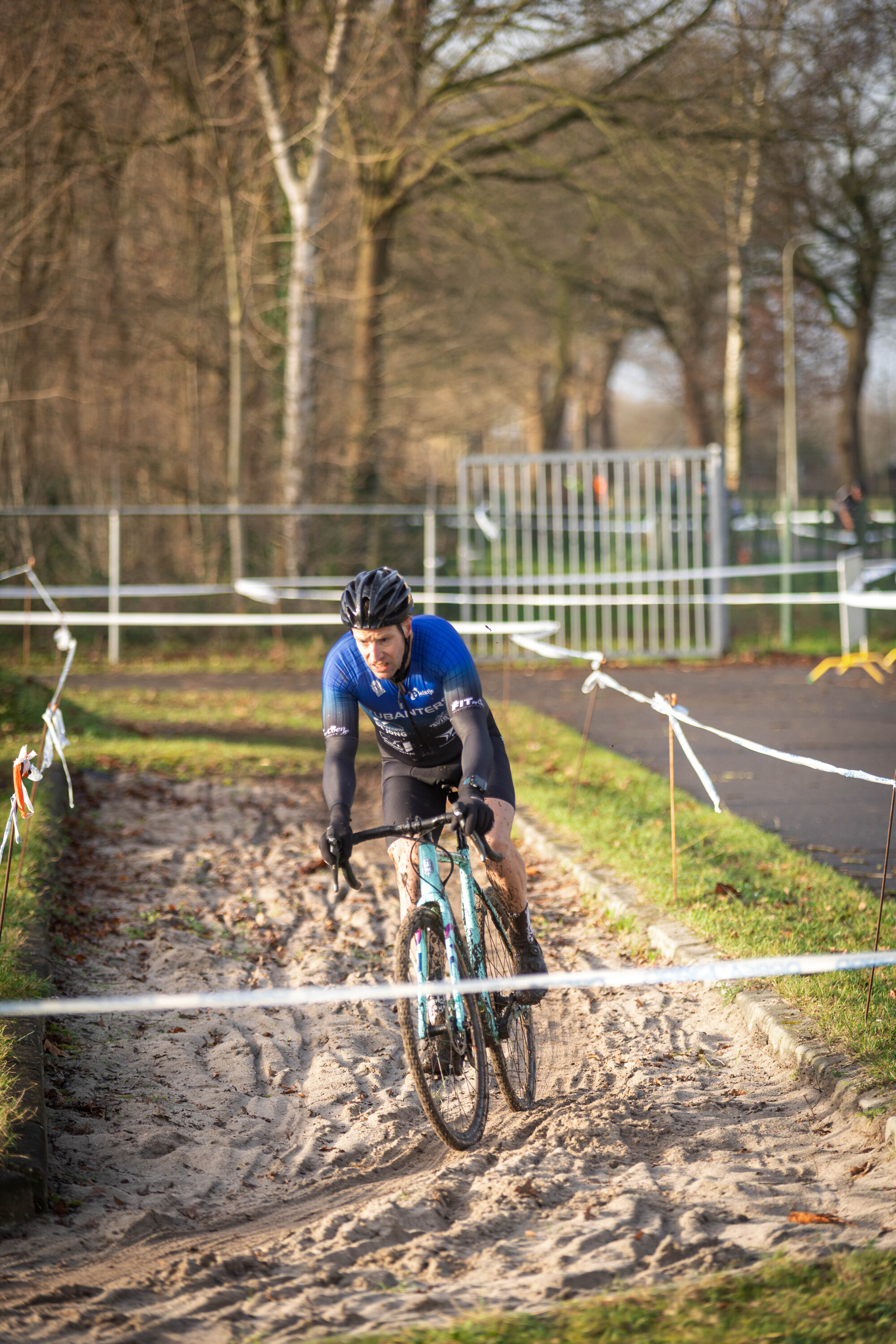 A man wearing a blue shirt is racing a bike on a dirt track.