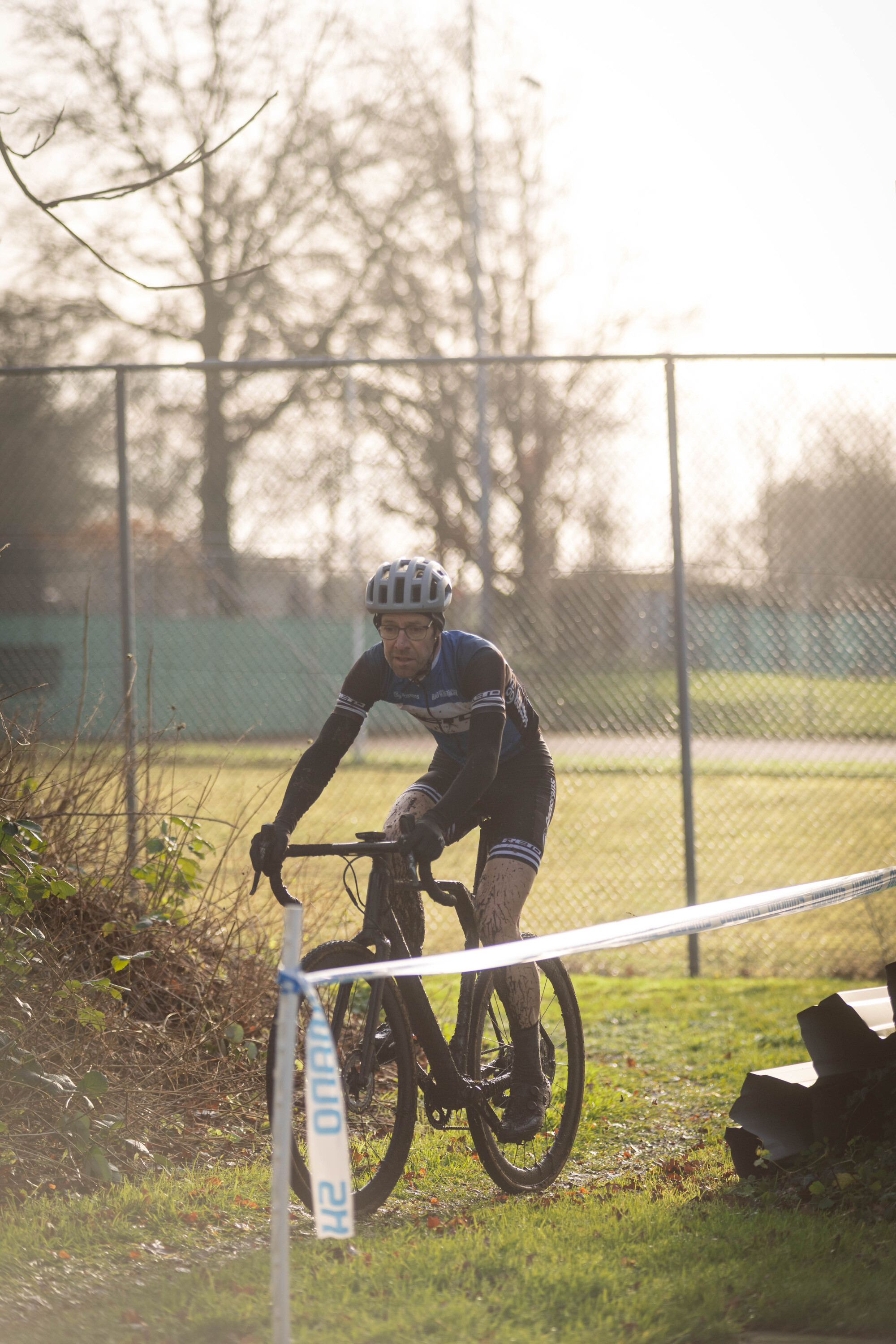 A man riding a bike past a sign that says Cyclocross.