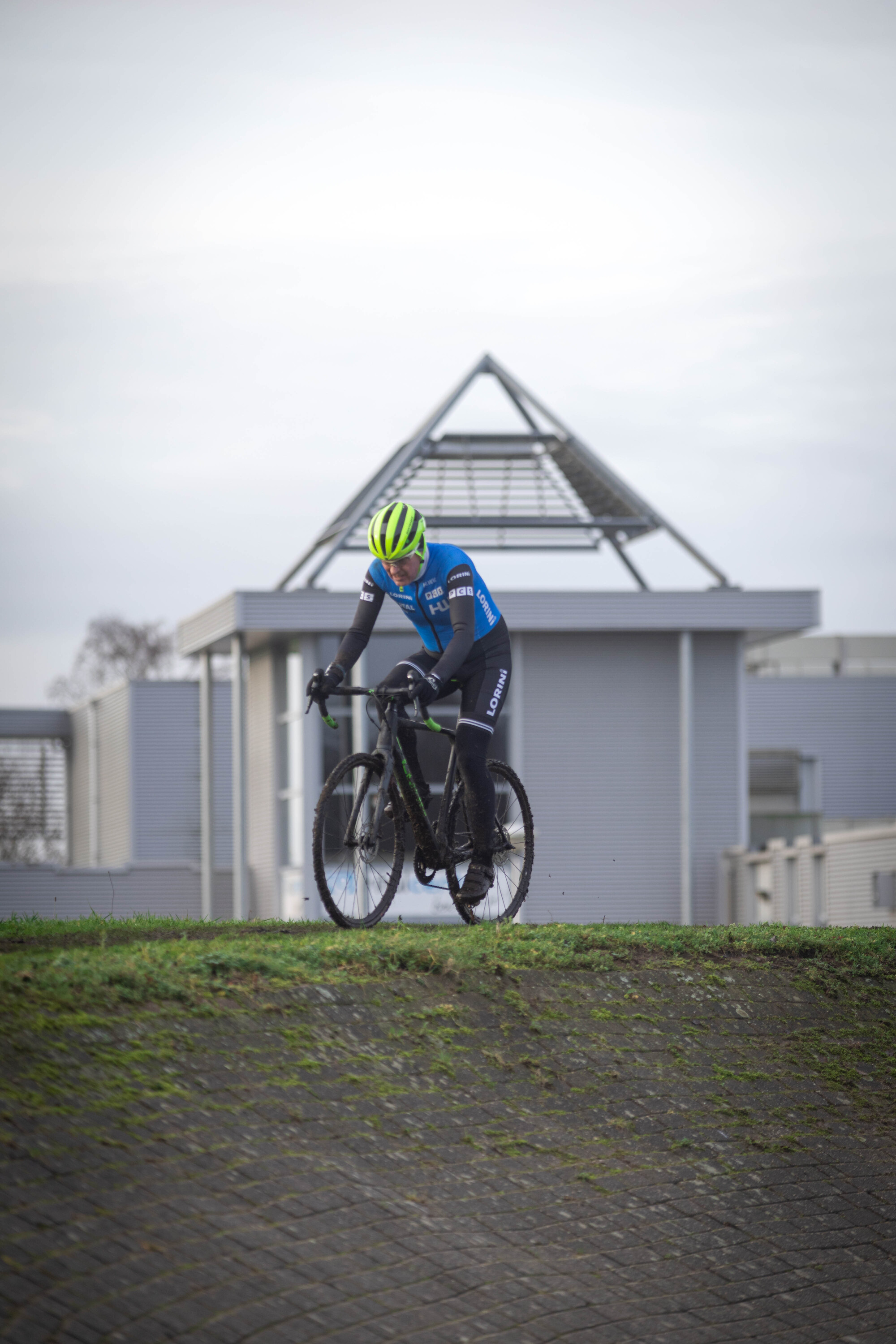 A man on a bicycle wearing a blue jersey and green helmet.