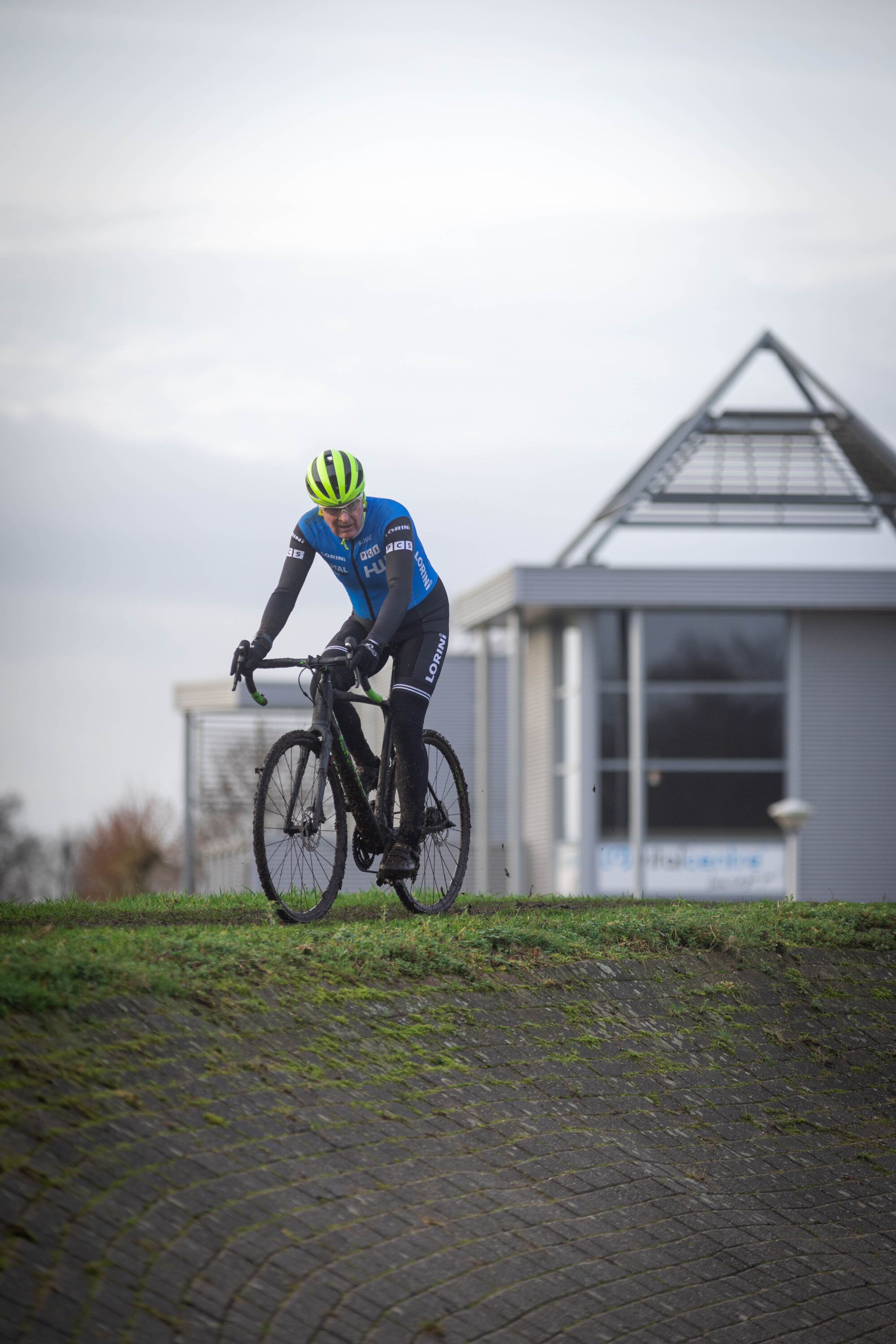 A cyclist wearing a blue shirt riding a bike in front of a building.