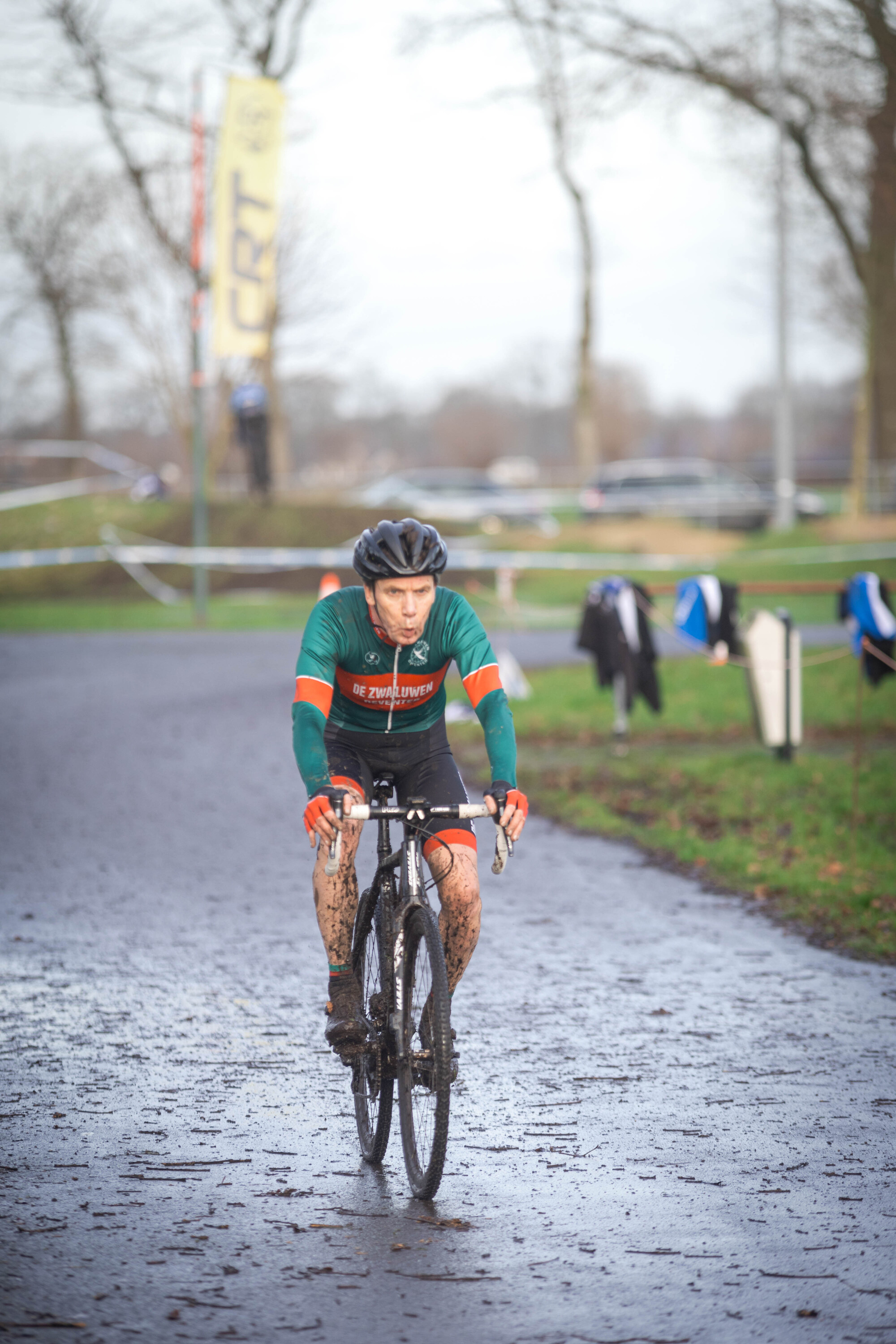 A man is riding a bike in the rain and has "GOW" on his jersey.