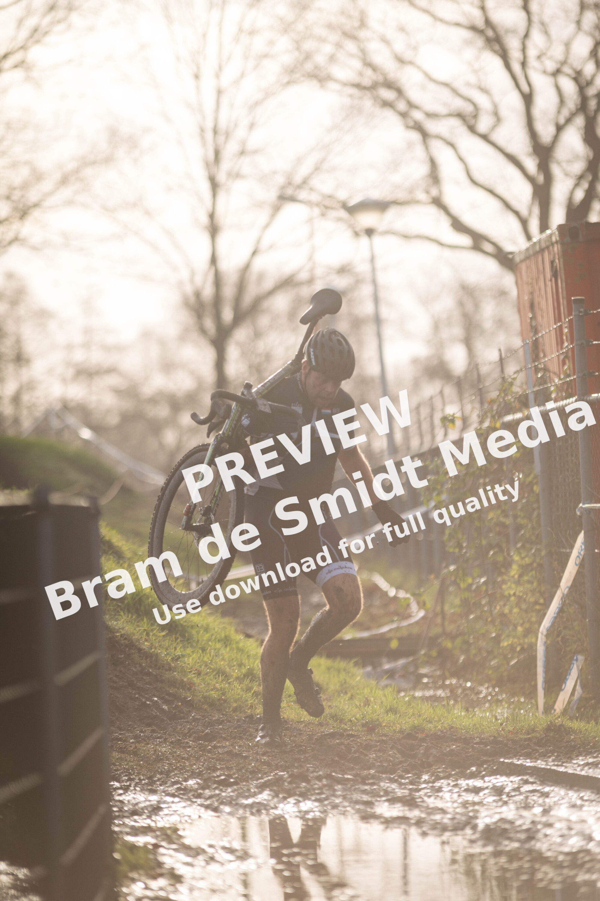 A person carrying a bicycle while wearing a helmet.