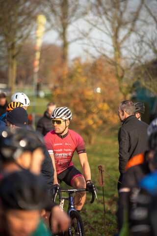 A group of people at a cyclocross event watch as the race progresses.