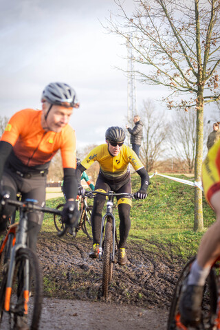 A group of cyclists in a cyclocross race with one rider who seems to be leading.