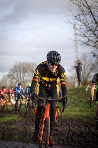 A cyclist is riding through mud in a race that has the number 2023 on it.