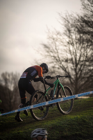 A man is racing on a green bike in a cycling event.