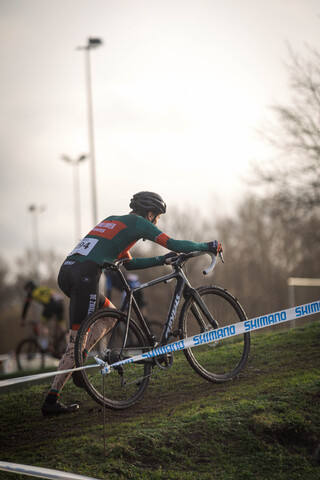 A person in a red and green shirt rides a bicycle on the track.