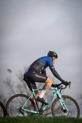 A man on a blue and white bike with the word cyclocross written on his outfit.