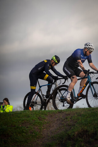 Three men are cycling and one of them is wearing a blue shirt with the word "GOW" on it.