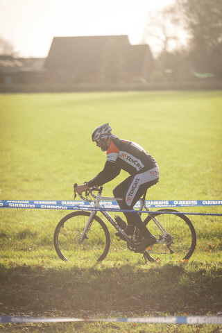 A man wearing a black and white jersey is riding his bicycle.