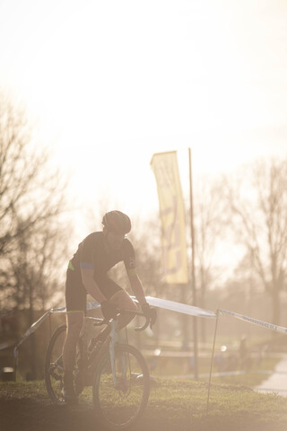 A man wearing a bike helmet on his head is riding a bicycle while holding the handlebars.