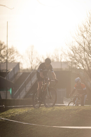 Two cyclists riding in a grassy area with one wearing the number 14 on his shirt.