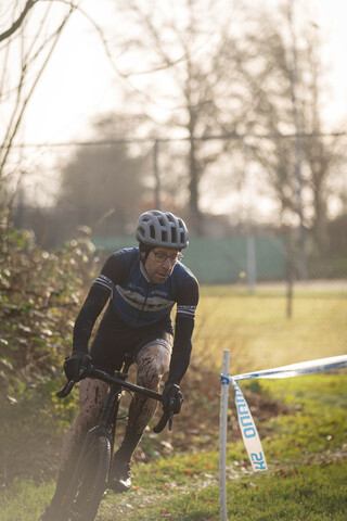 A man in a black and blue cycling outfit rides his bike through a course of obstacles.