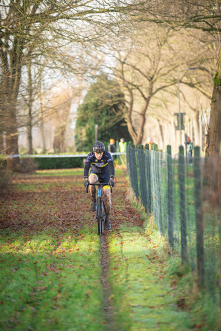 A man wearing a helmet on his bicycle while riding on a path in an open field.