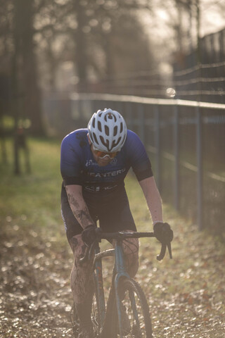 A man wearing a helmet is riding his bike down a path. He's wearing shorts and sunglasses.