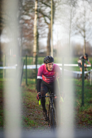 A cyclist with a pink shirt that has the word Masters written on it.