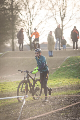 A man wearing a black helmet is riding his bike through an obstacle course.