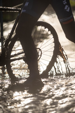 A person on a cross country bike wearing black with a small logo on the back.