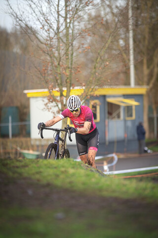 A cyclist in a pink and black uniform rides a blue and black mountain bike.