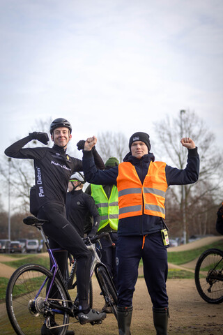 A group of cyclists in a forest with their arms raised.