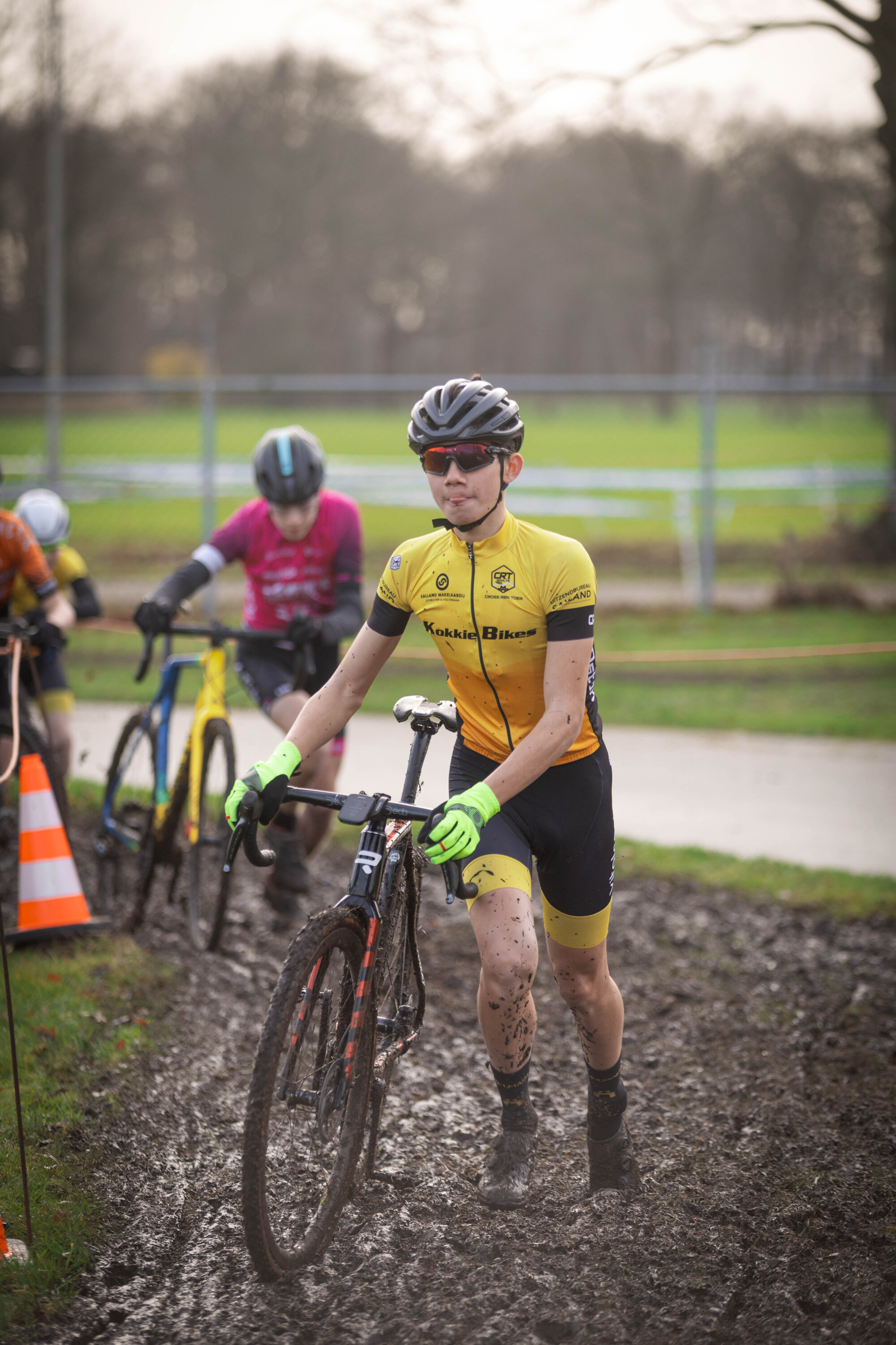 A man is riding a muddy bike wearing a yellow and black jersey with the number 24 on it.