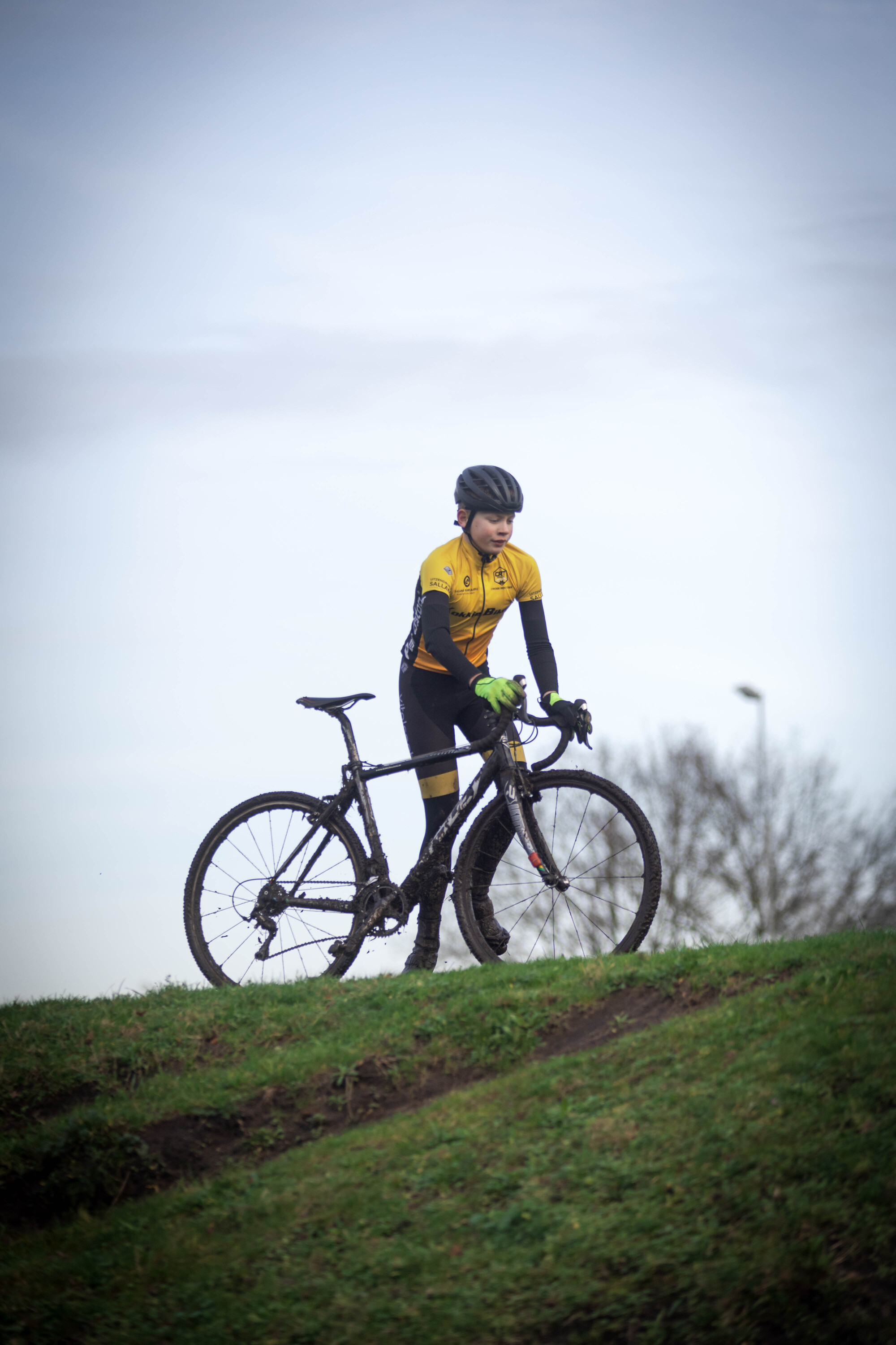 A person on a mountain bike wearing yellow and black is looking at the camera.