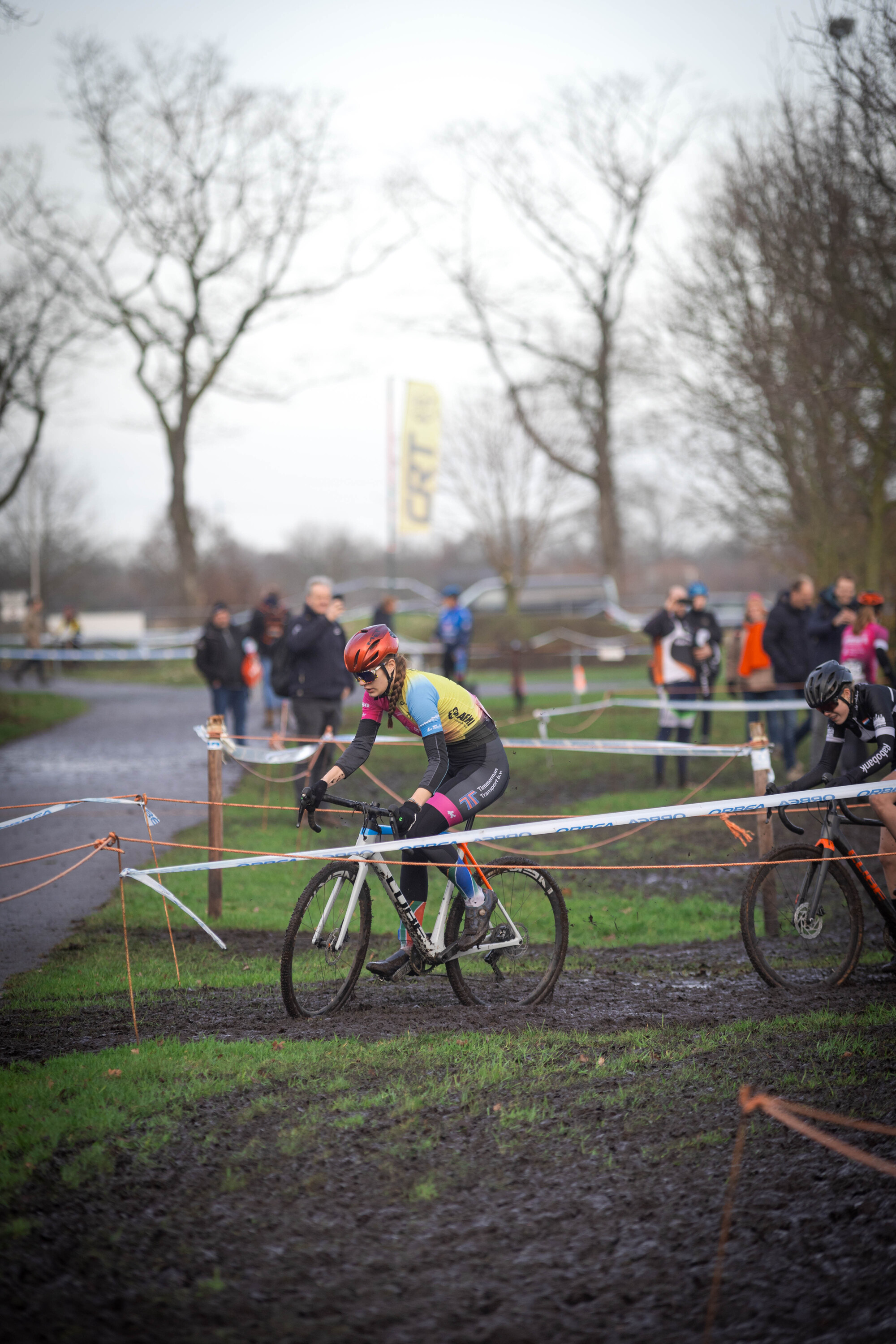 A man wearing a red helmet is riding a bike around a course.