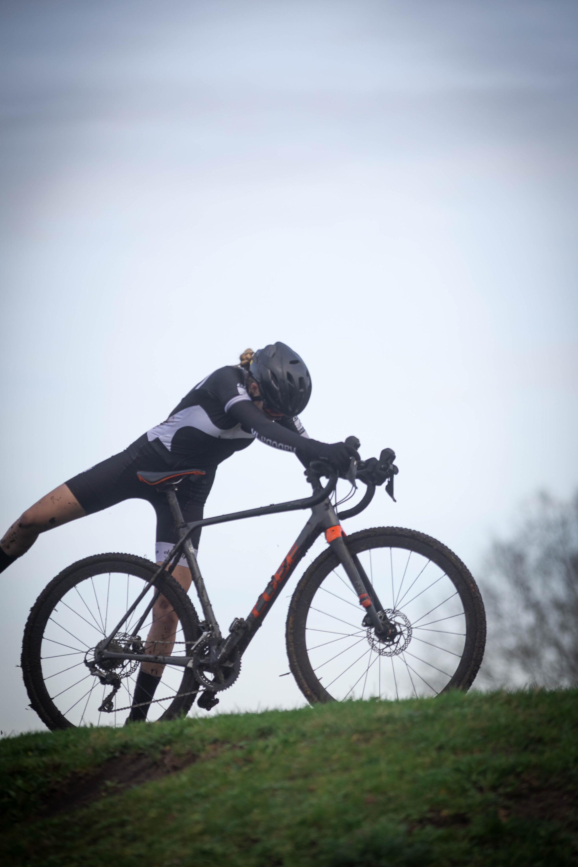 A person in a black and white cycling suit on a bike.