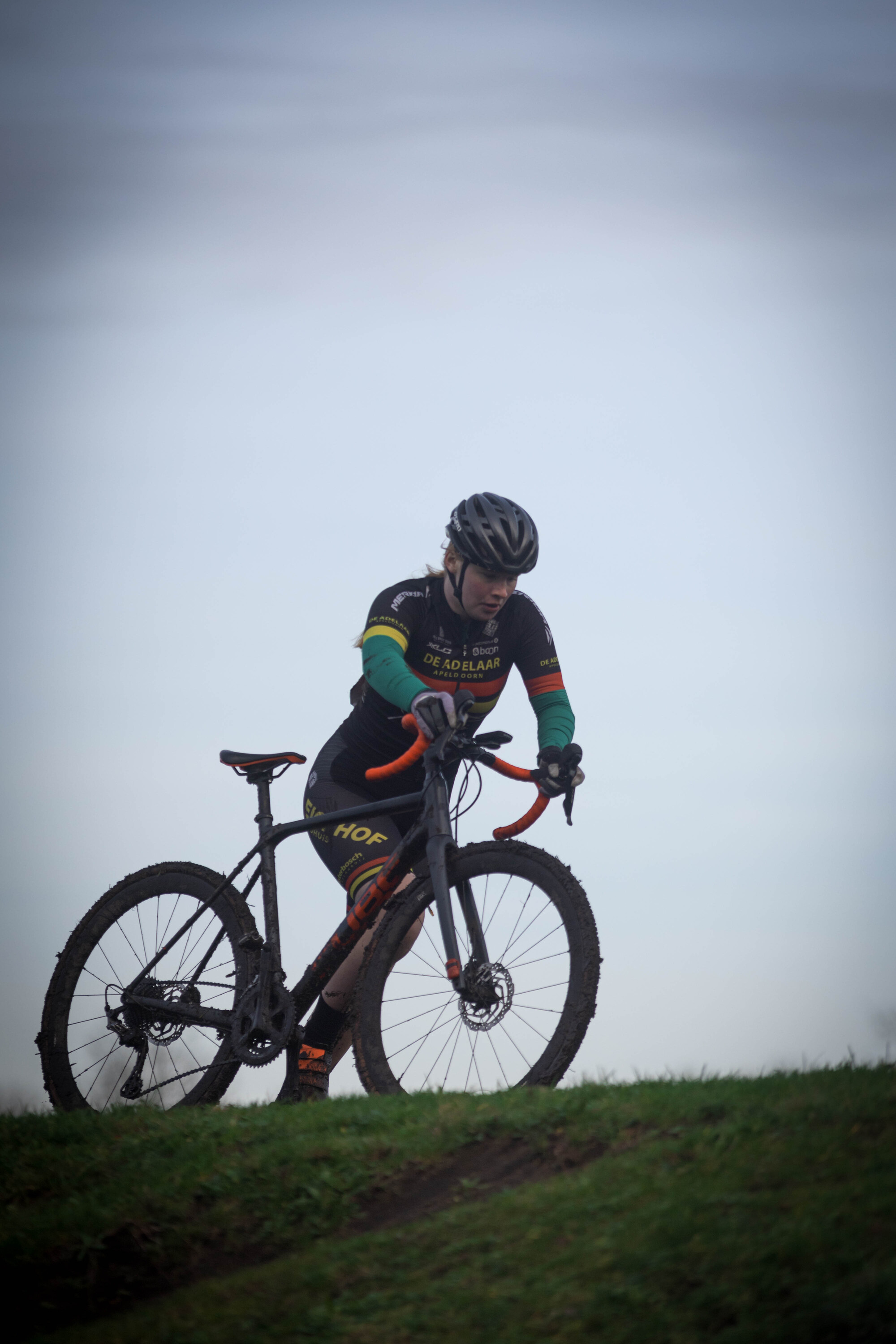 A man riding a mountain bike with a helmet on. The sky is clear and blue.