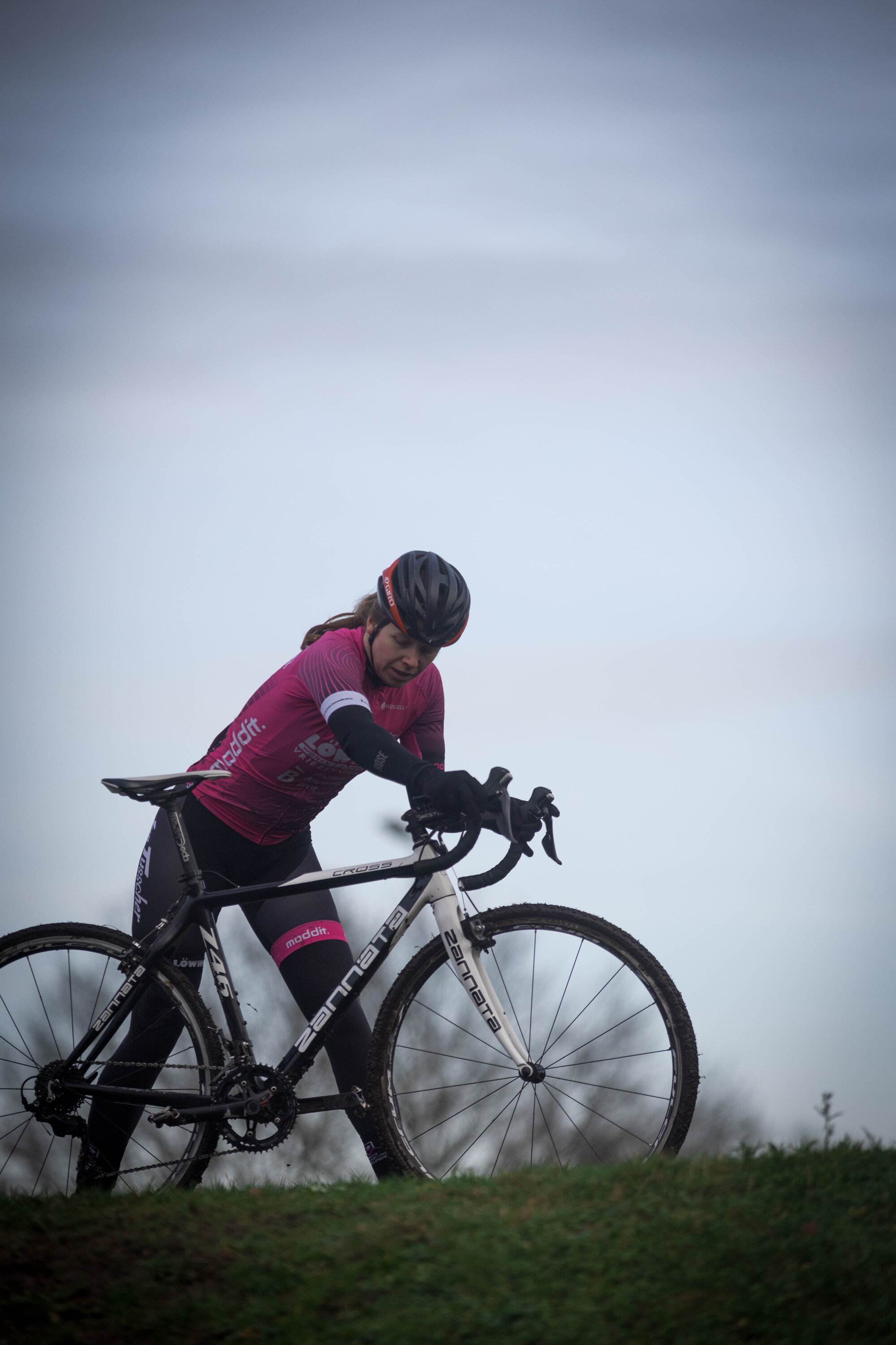 A woman wearing a pink outfit is on a black and white bike.