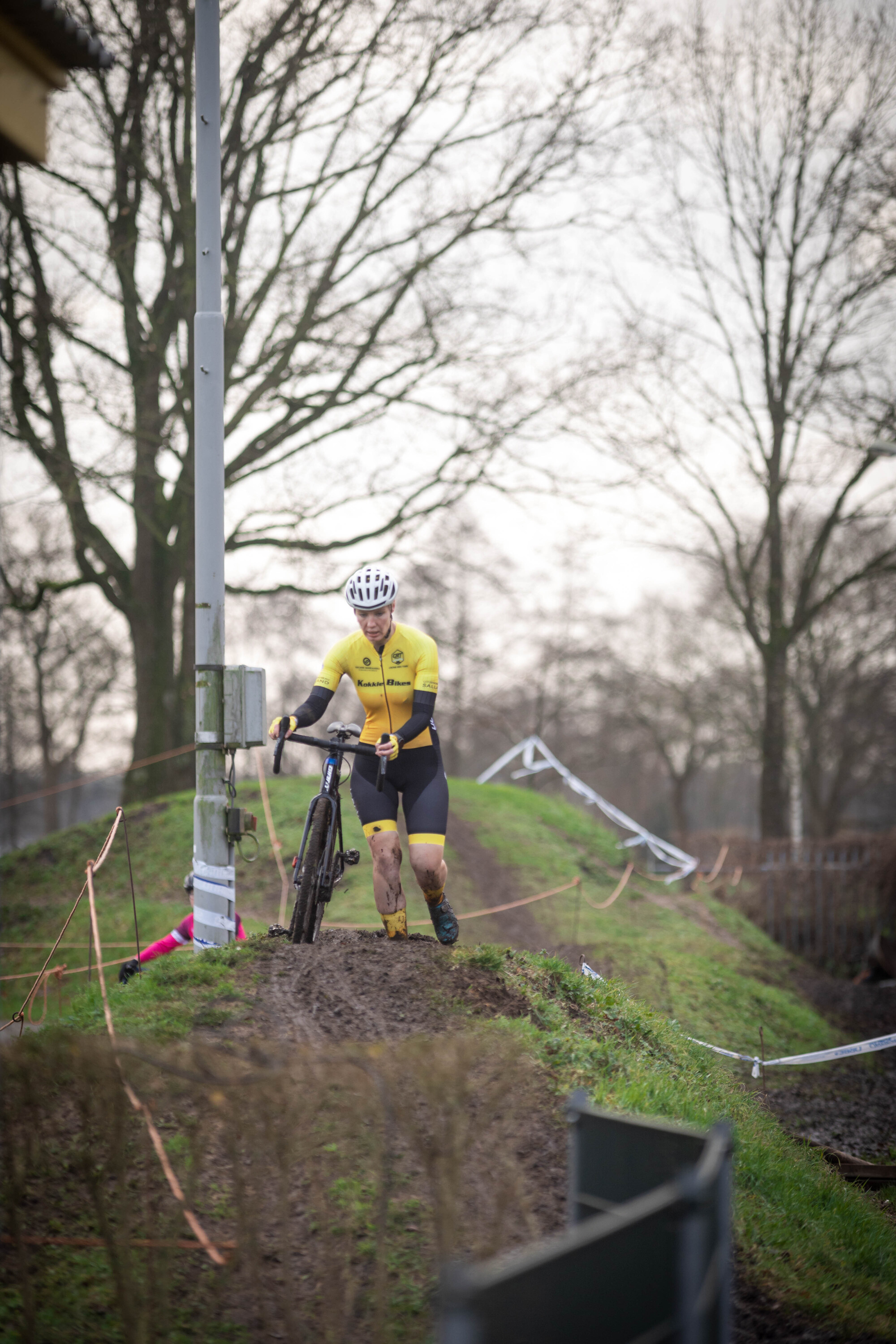 A person wearing a yellow shirt and black pants is riding a bike down a hill.