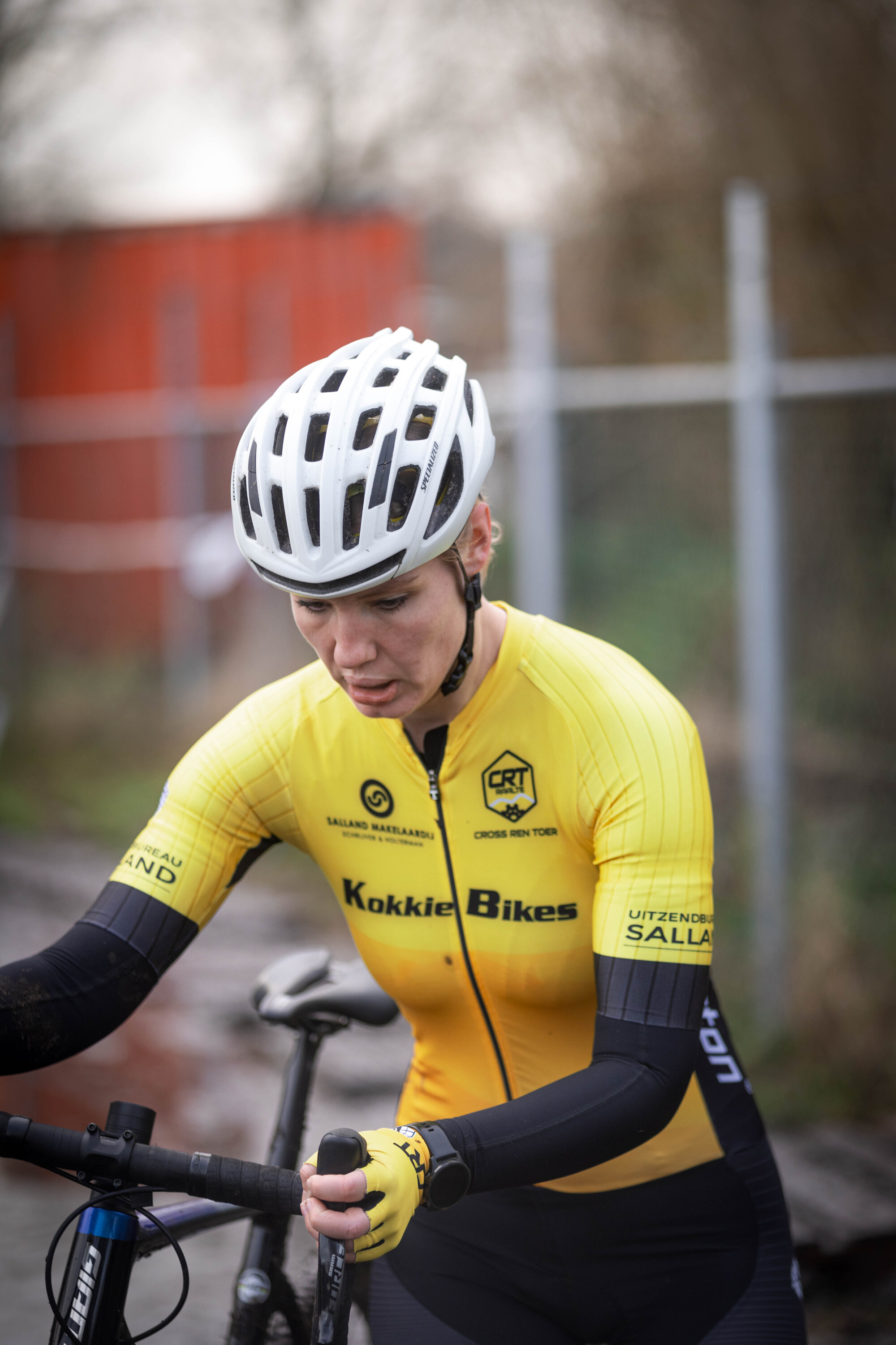 A cyclist in a yellow shirt and white helmet is riding on the road.