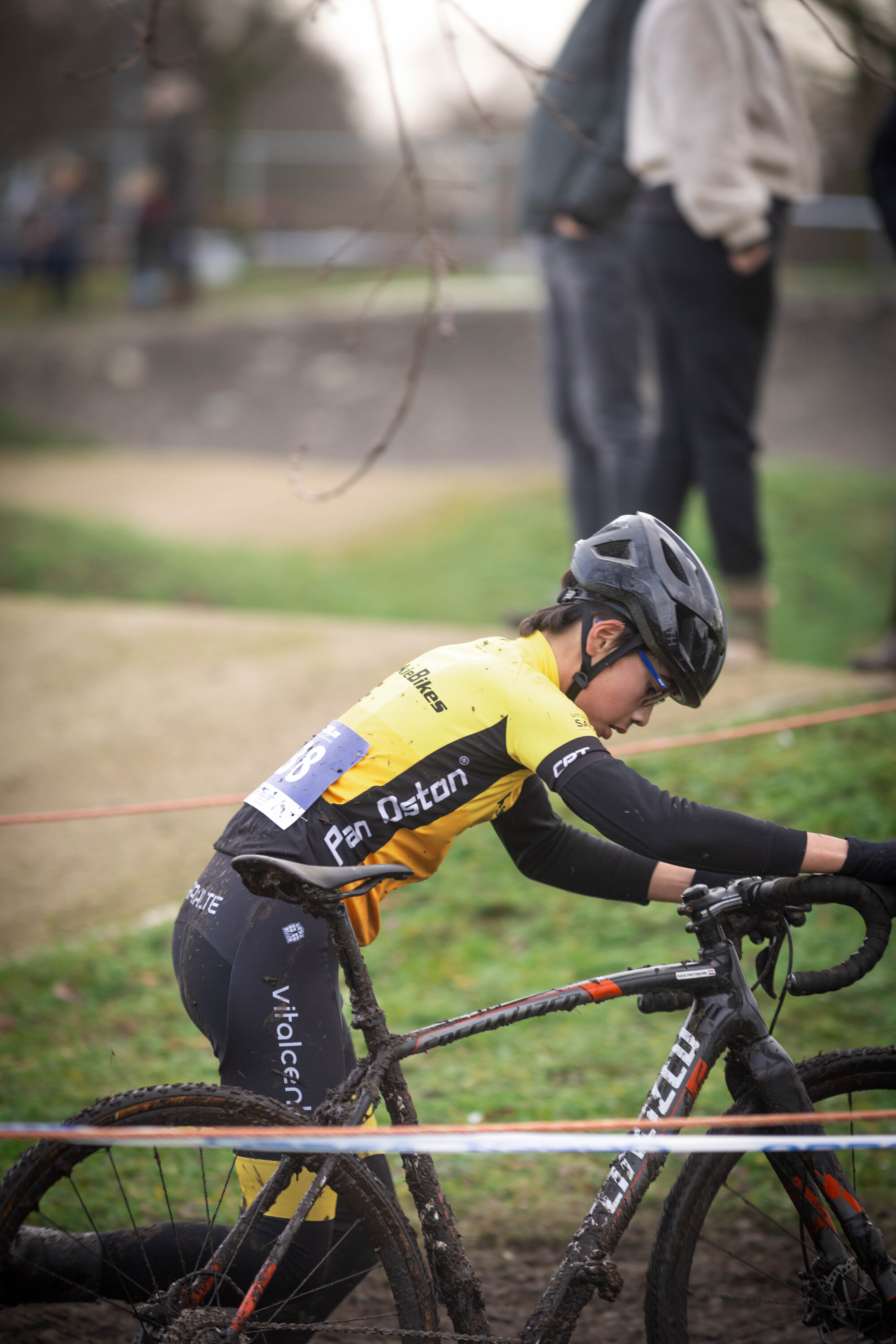 A person is riding a black bicycle with a yellow shirt that says "Gow Raalte".