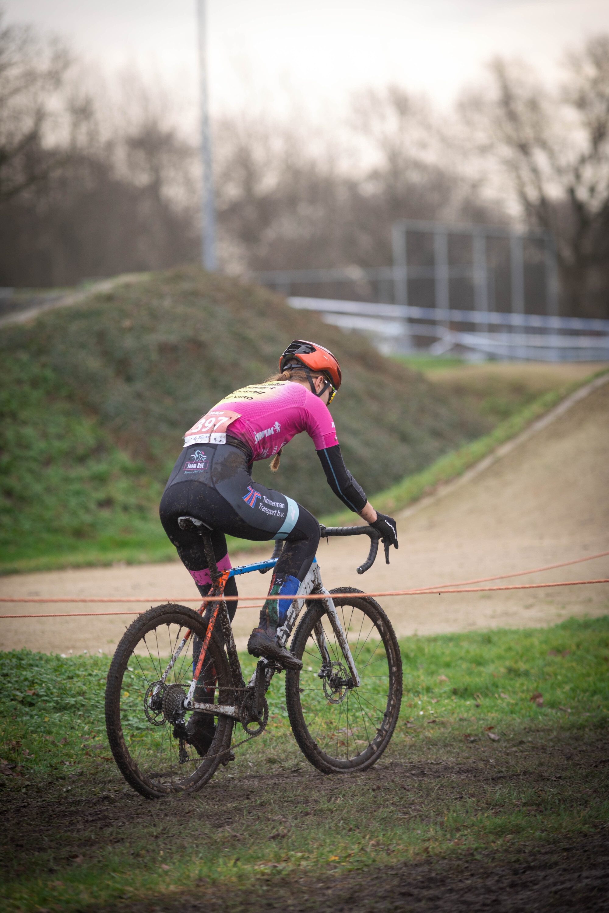 Cyclocross racer wearing a pink jersey on a dirt track.