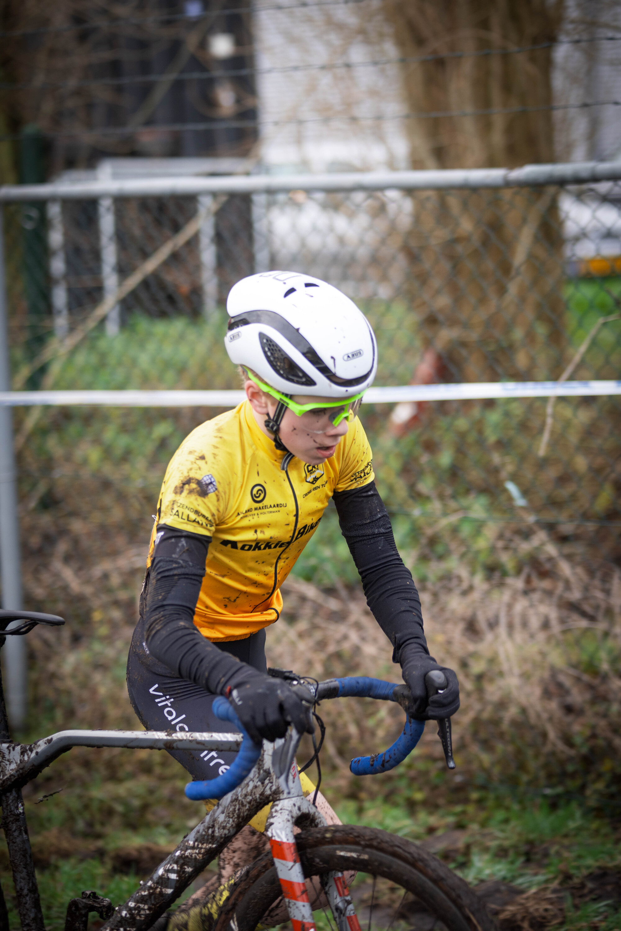 A cyclist wearing a white helmet is in motion on a bike with blue handlebars.