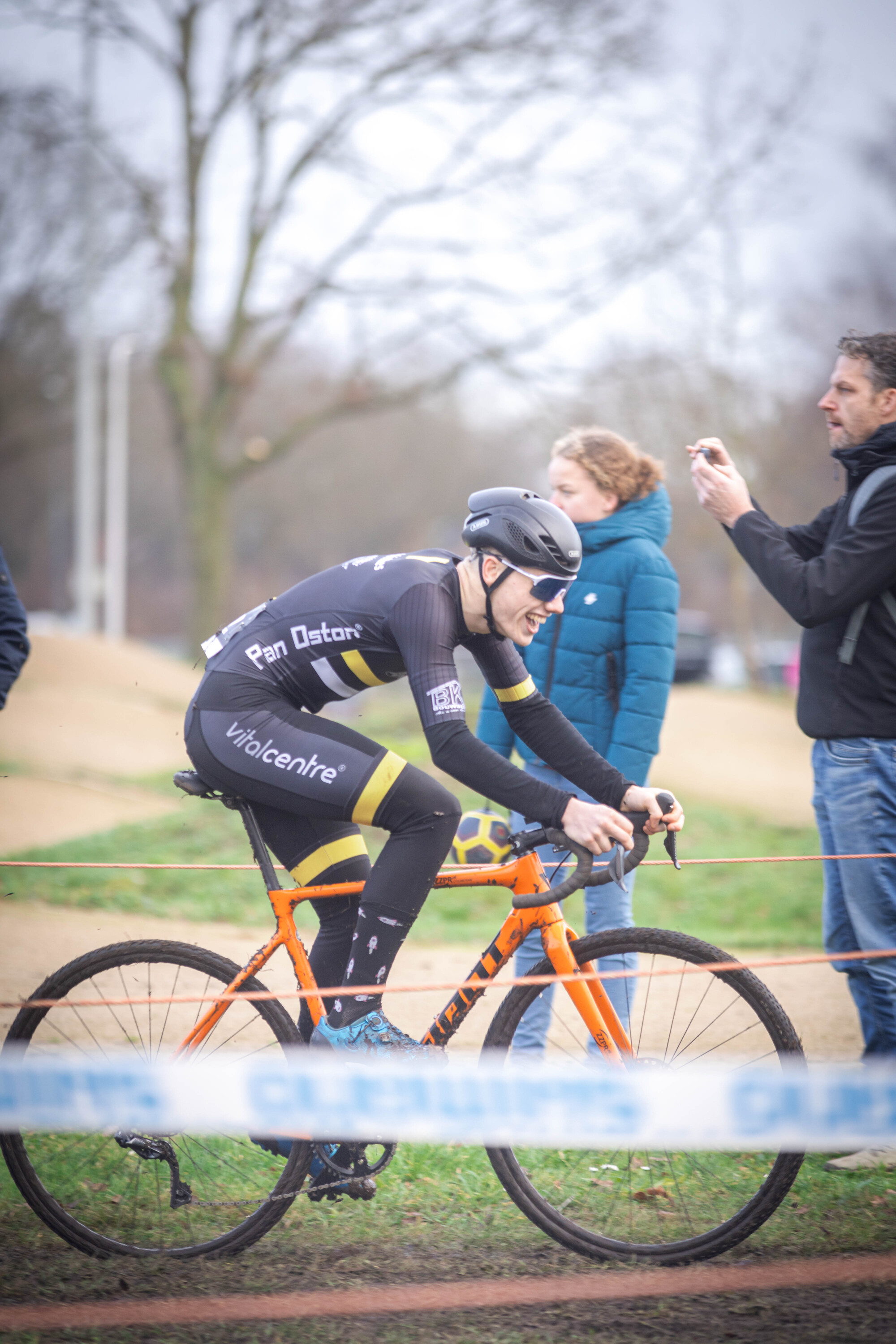 A man on a bike in front of people wearing blue and black.