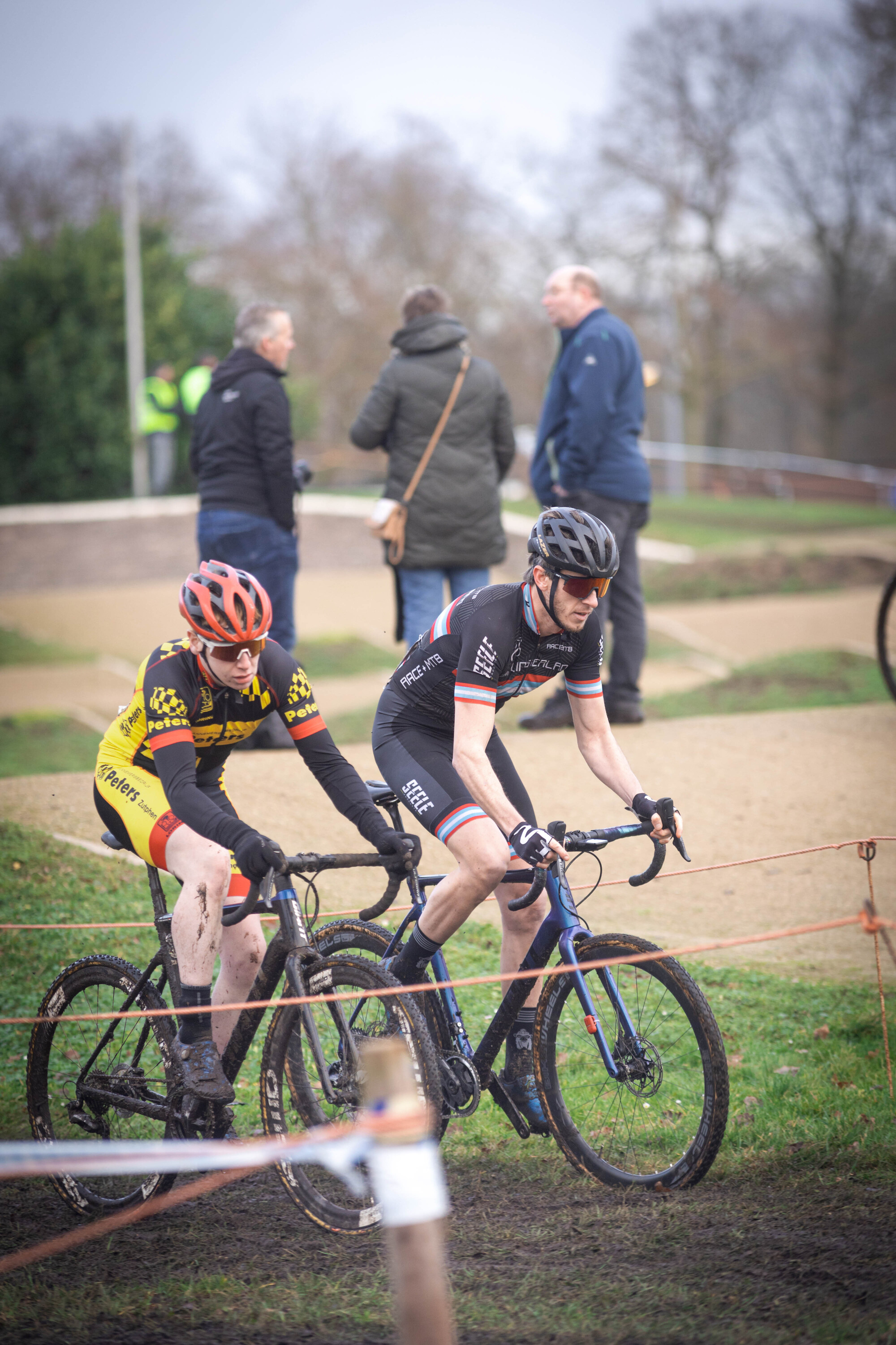 A cyclist in a black shirt and blue shorts is racing to the left.