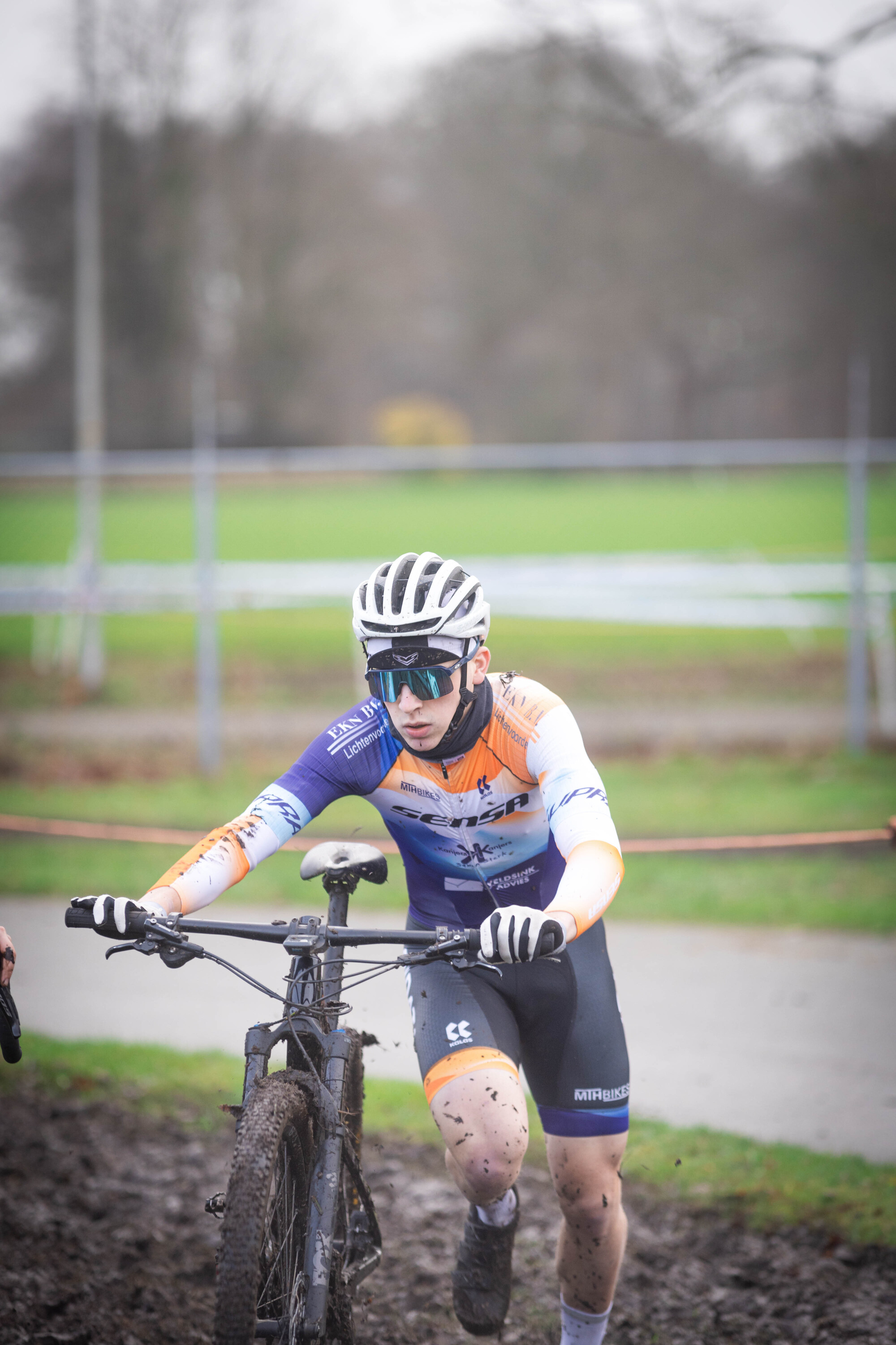 A young man on a bike wearing a purple and white Cycling Union jersey.