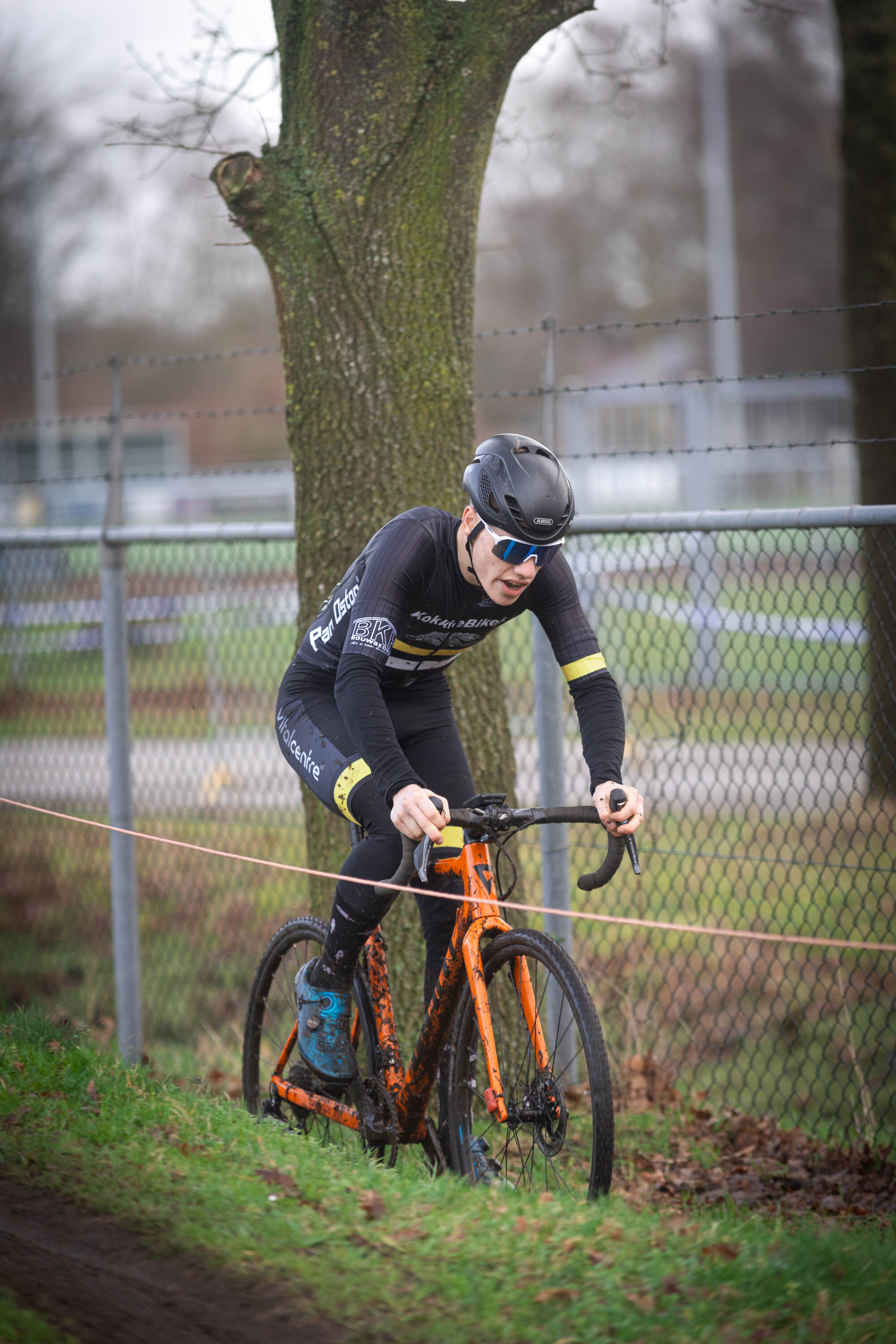 A man on a bike wearing a black and yellow cycling suit.