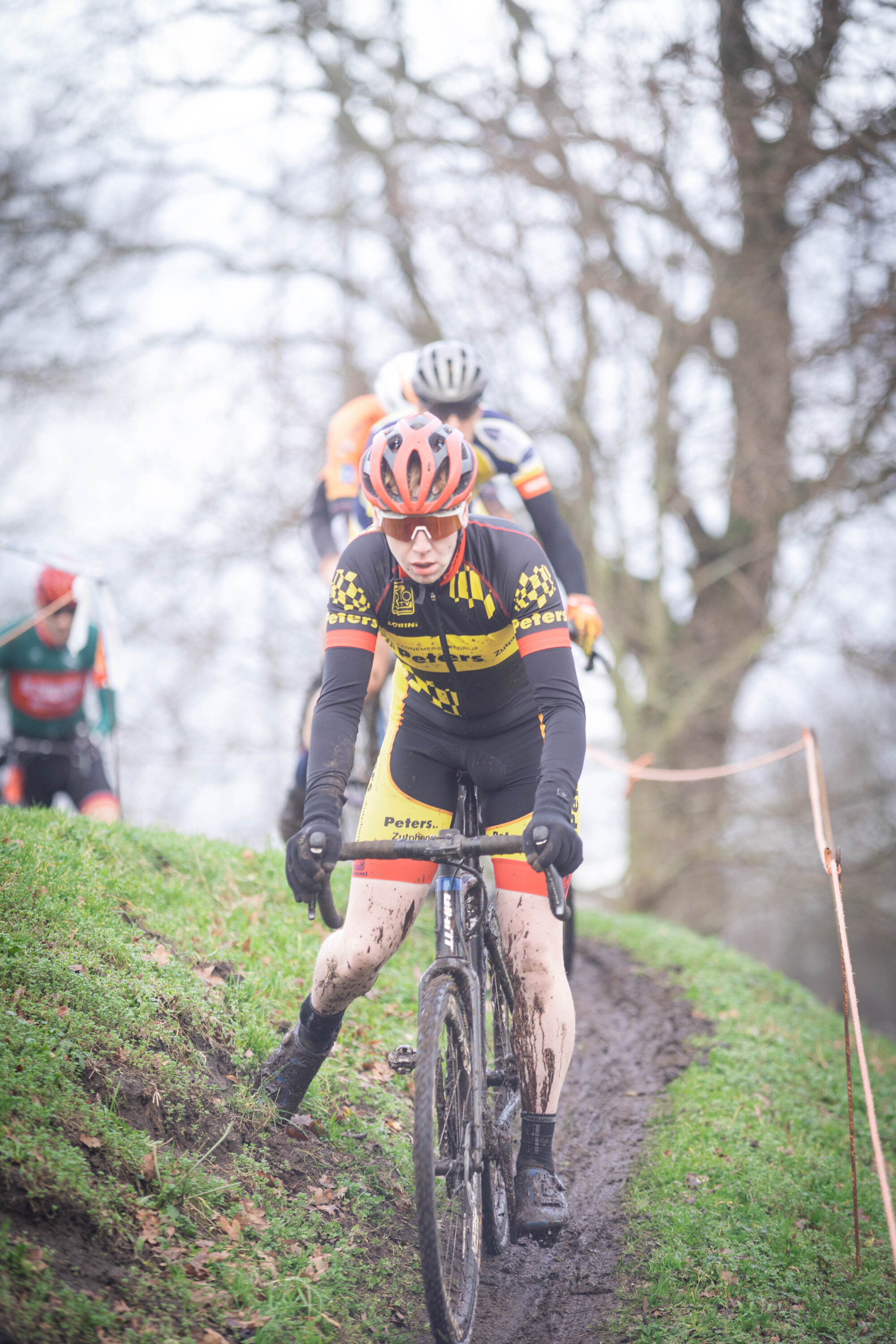 A person with a black and yellow jersey on riding a bike.