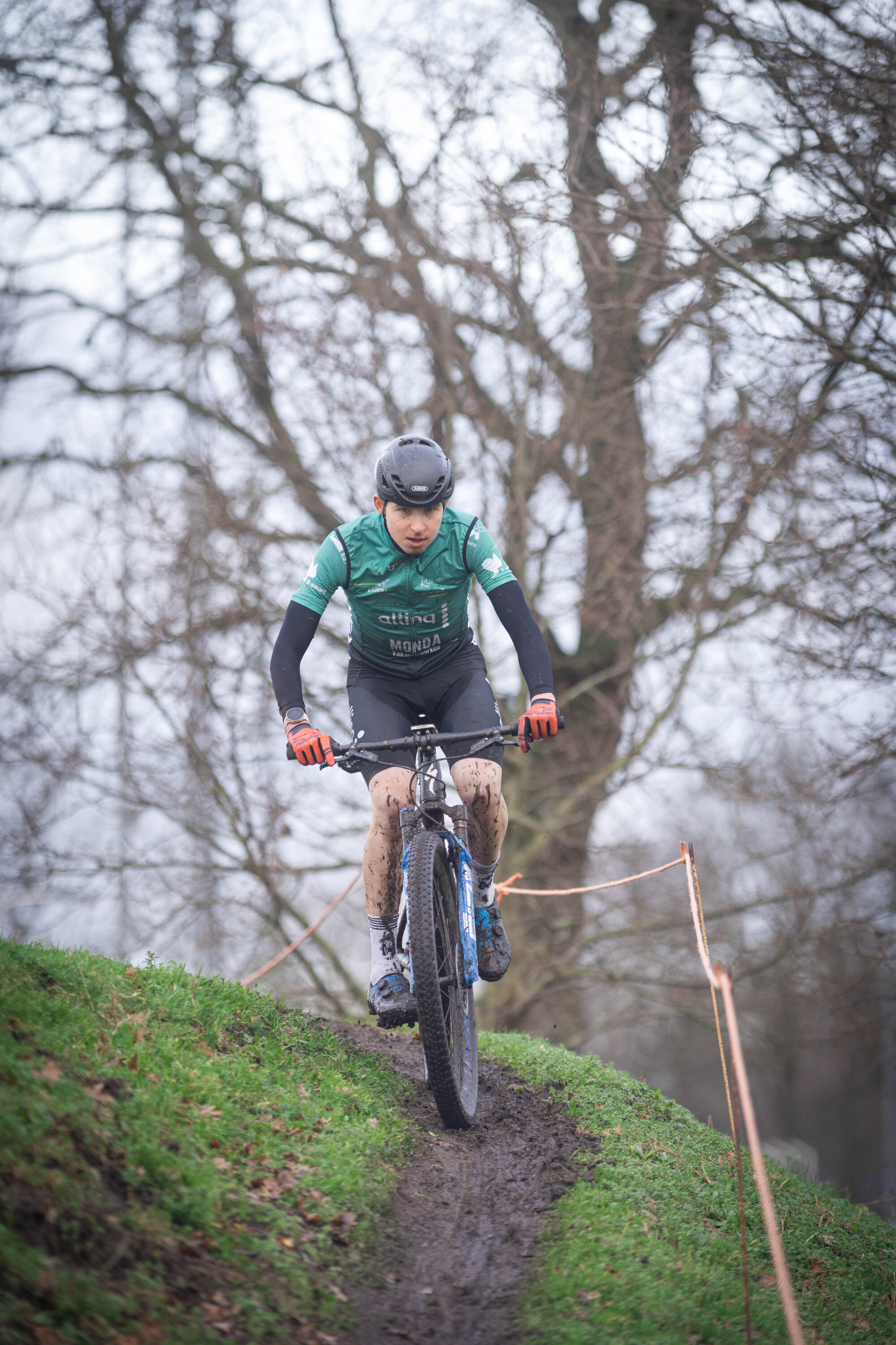 A cyclist wearing a blue shirt with the numbers 1 and 2 on it is riding a bike through a field.