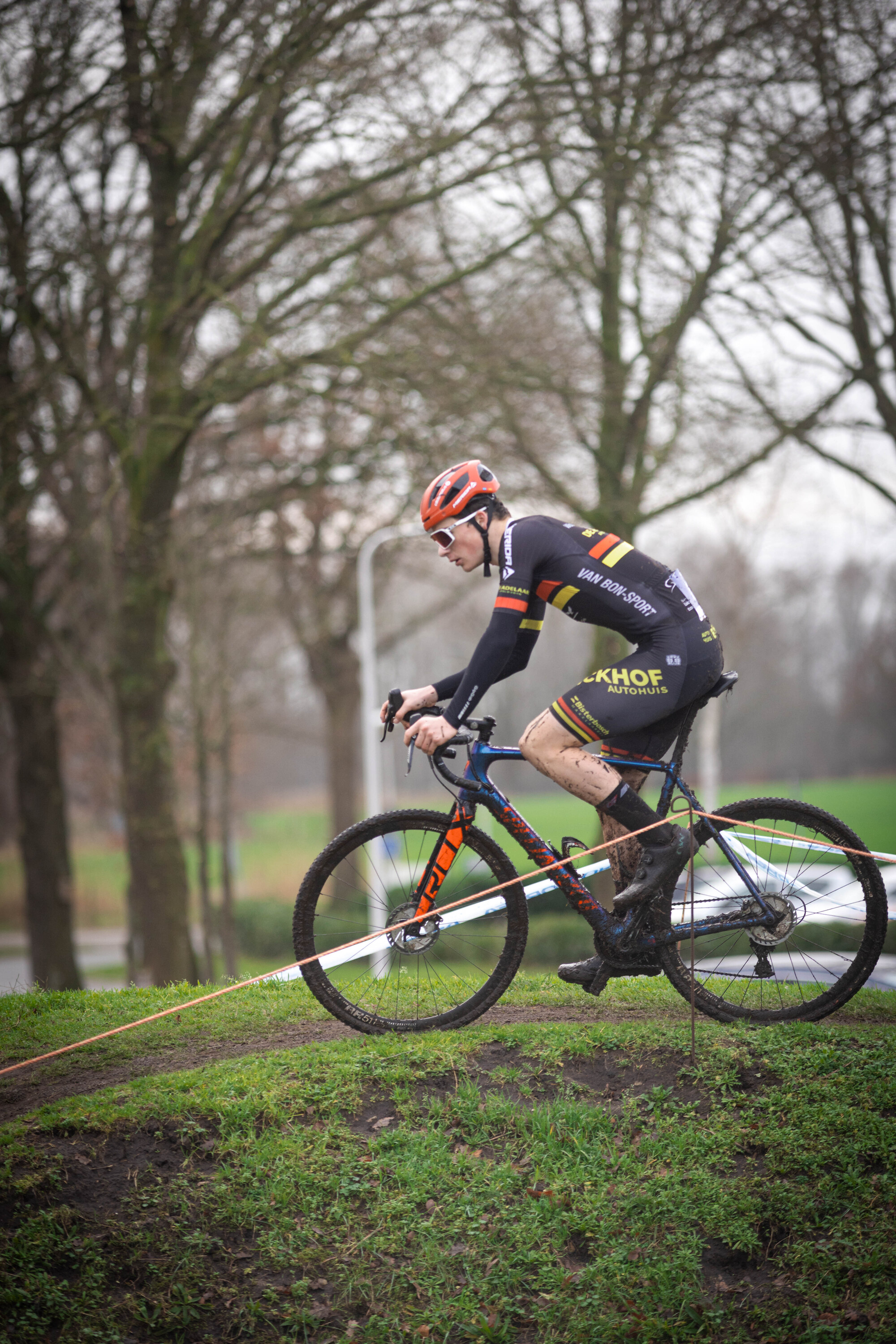 A person in a black and yellow race uniform riding a mountain bike.