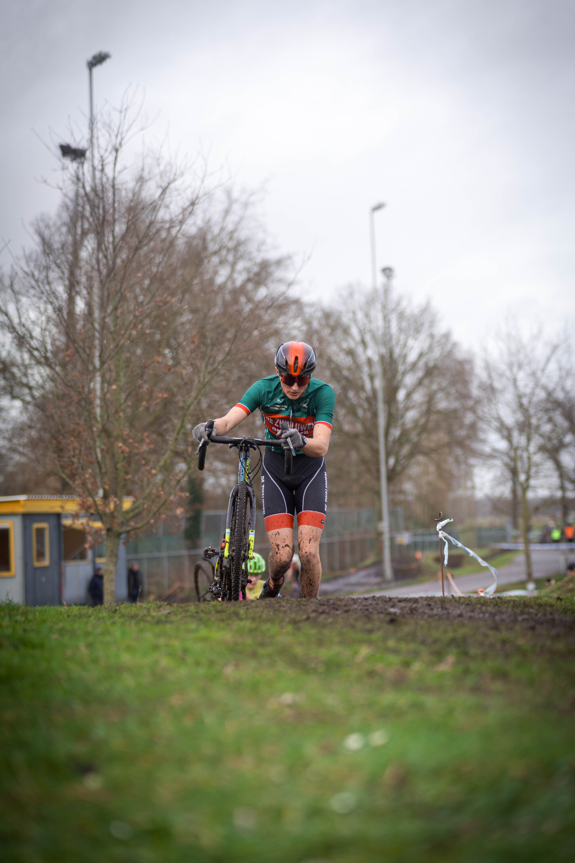 A person in a green and orange bike jersey rides a bicycle.